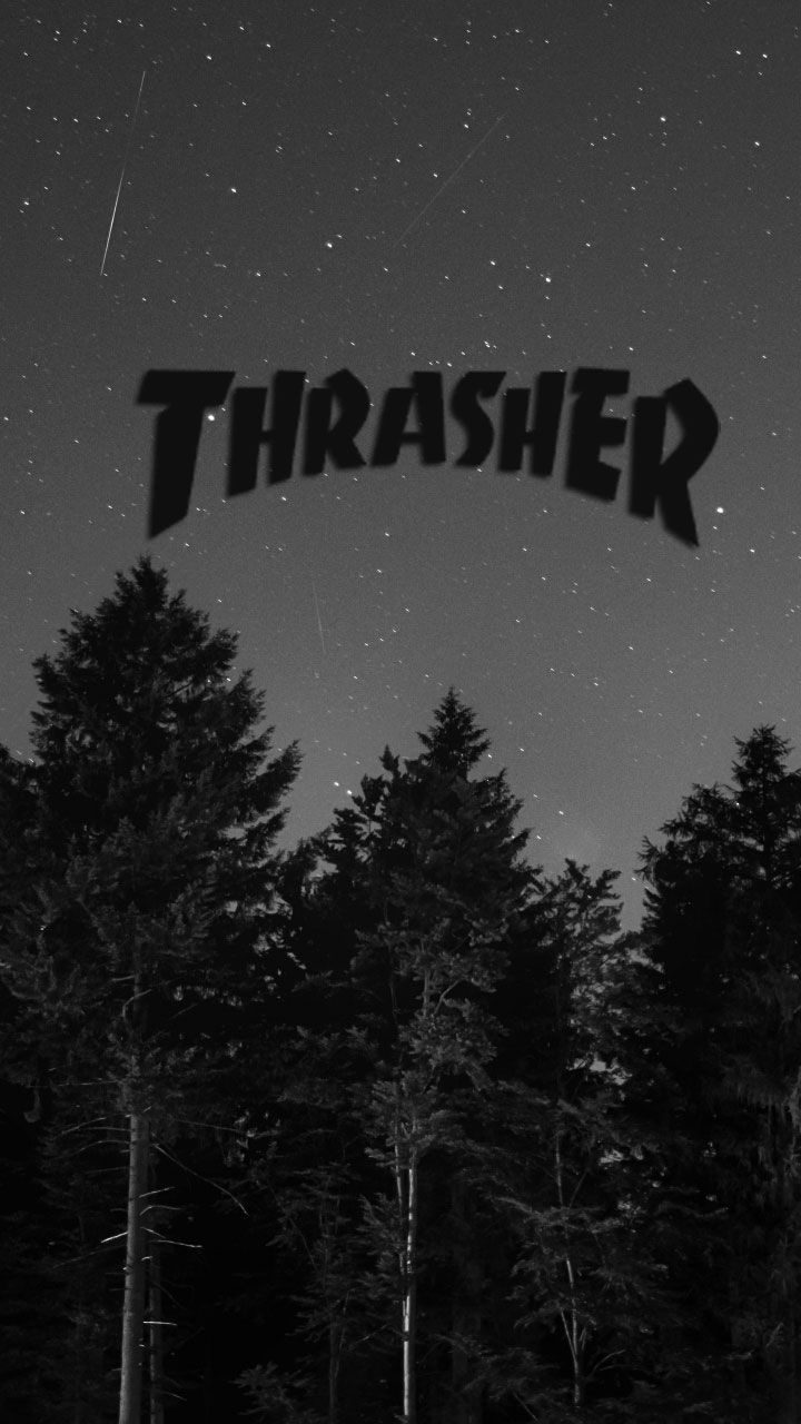 A black and white photo of the Thrasher logo over a forest at night - Thrasher