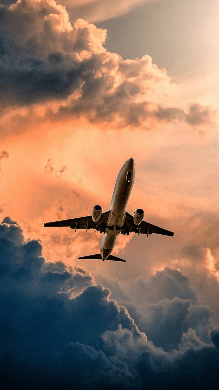 A plane flying through a cloudy sky at sunset - Airplane