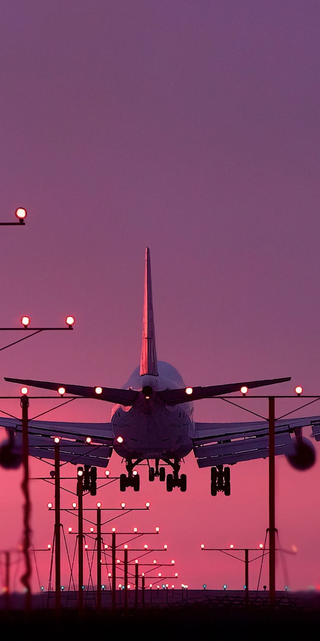 A plane landing at dusk with the runway lights illuminating the scene - Airplane