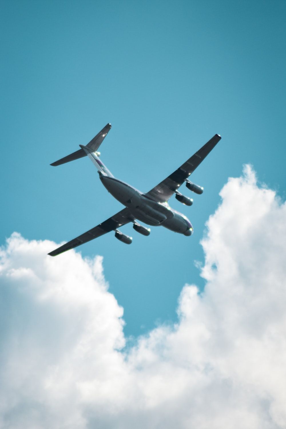 A large airplane flying through a cloudy blue sky. - Airplane