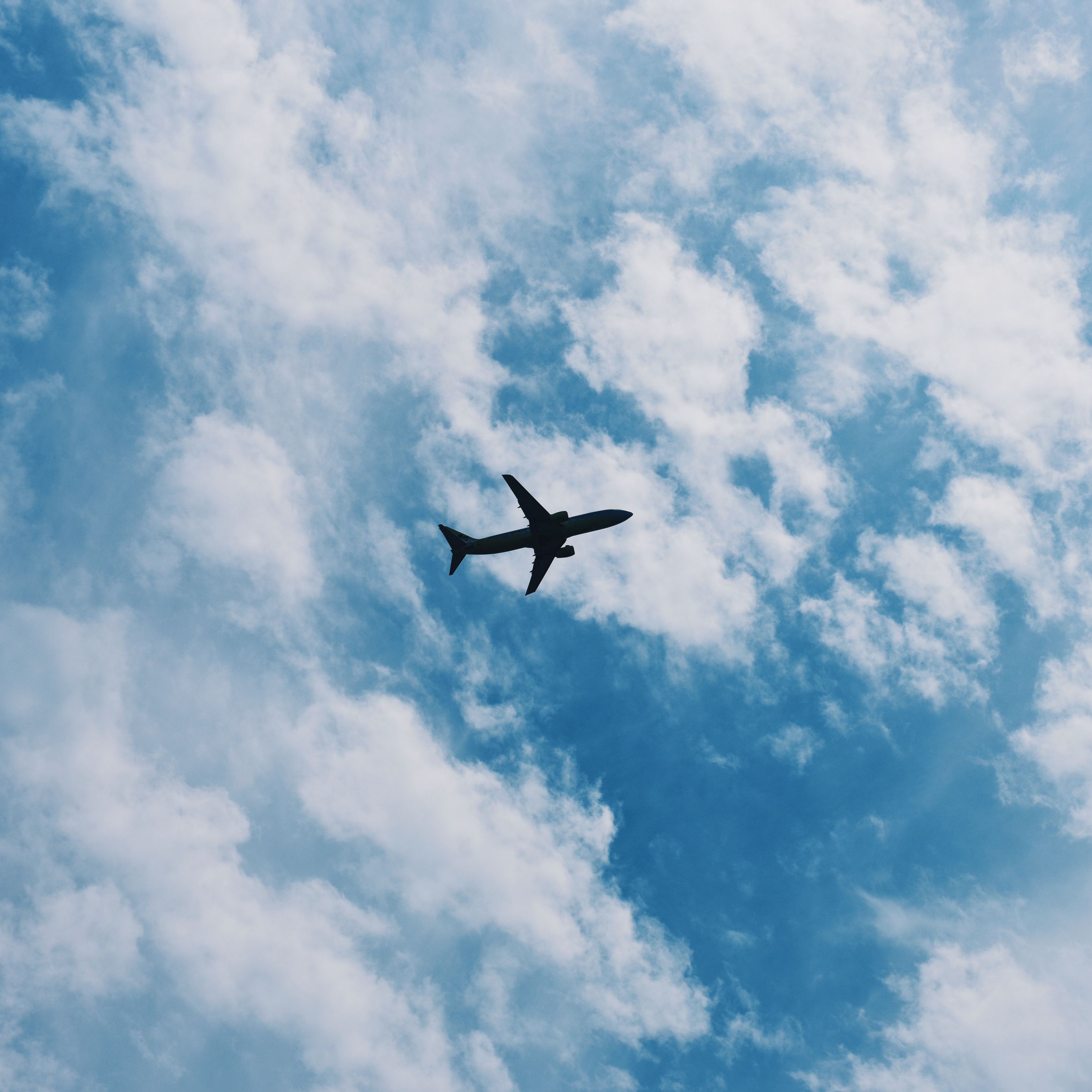 A plane flying through the clouds in blue sky - Airplane