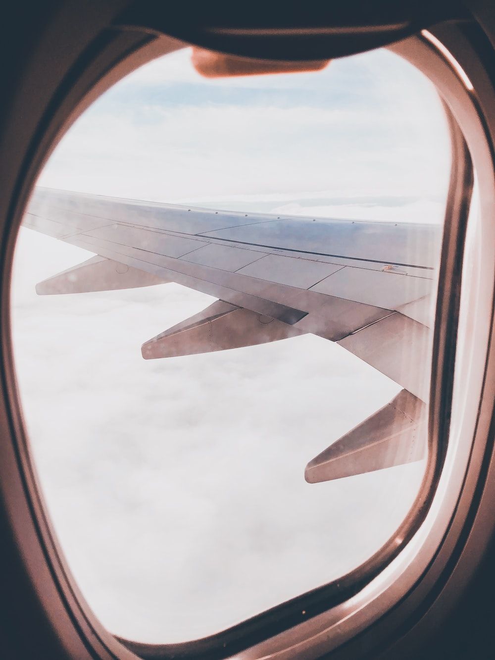 A window on an airplane looking out at the clouds - Airplane