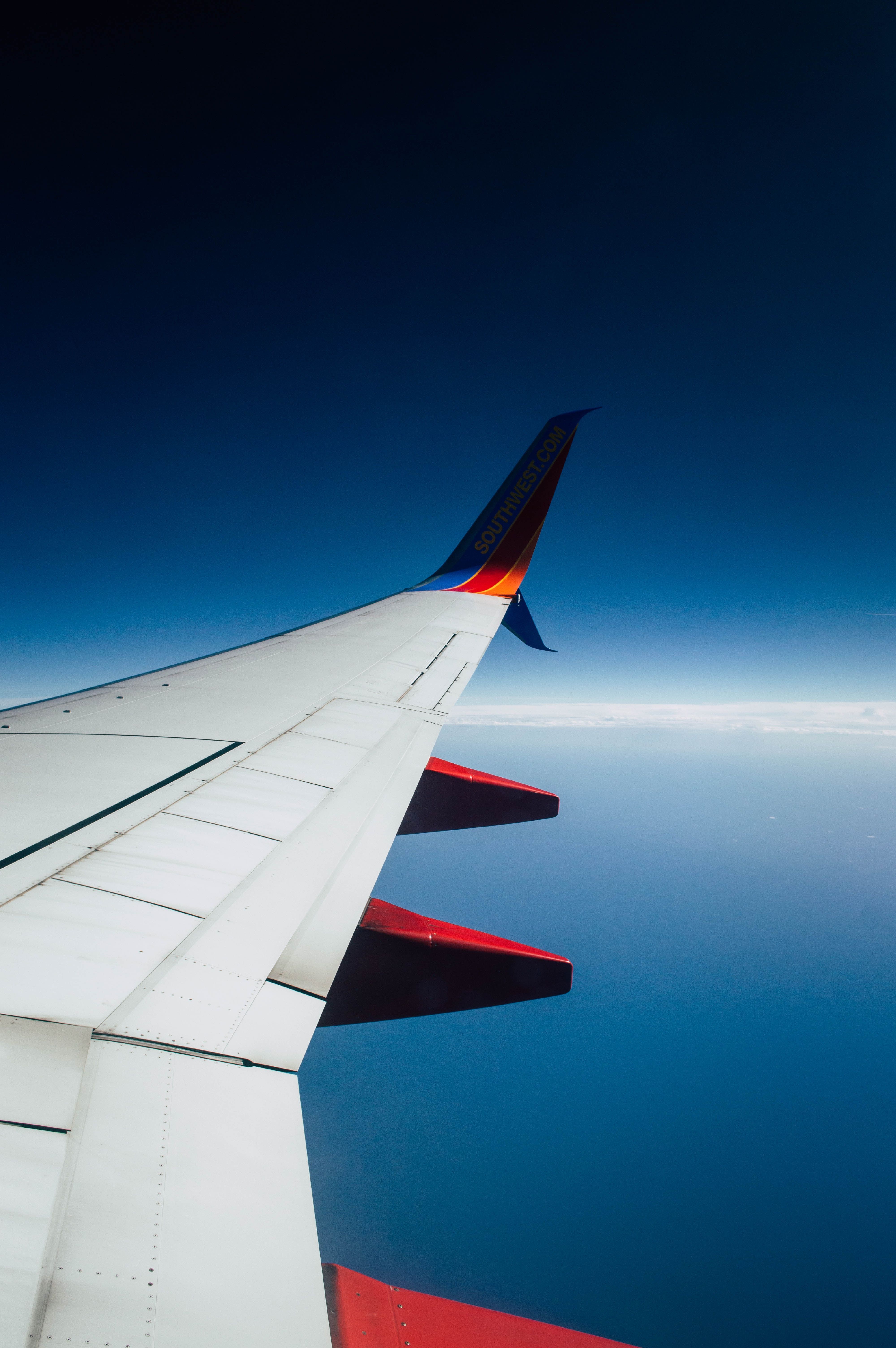 A wing of an airplane flying over the ocean - Airplane