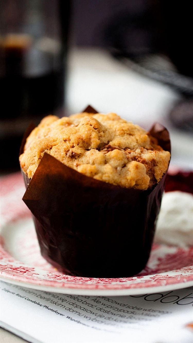 A muffin in a brown muffin case on a plate - 