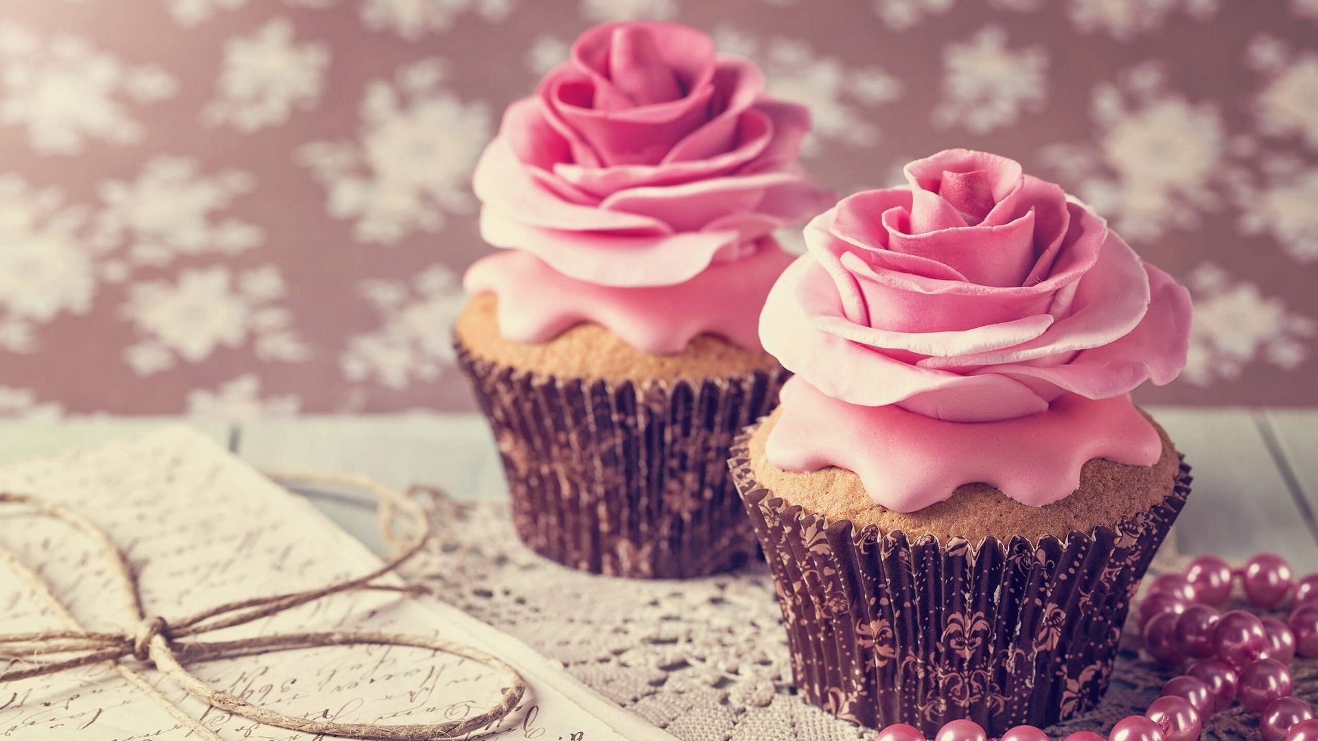 Two cupcakes with pink frosting and roses on top - 