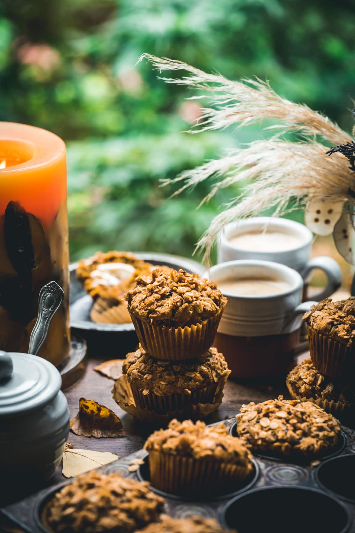 A muffin tray filled with muffins, a cup of coffee, and a candle. - 