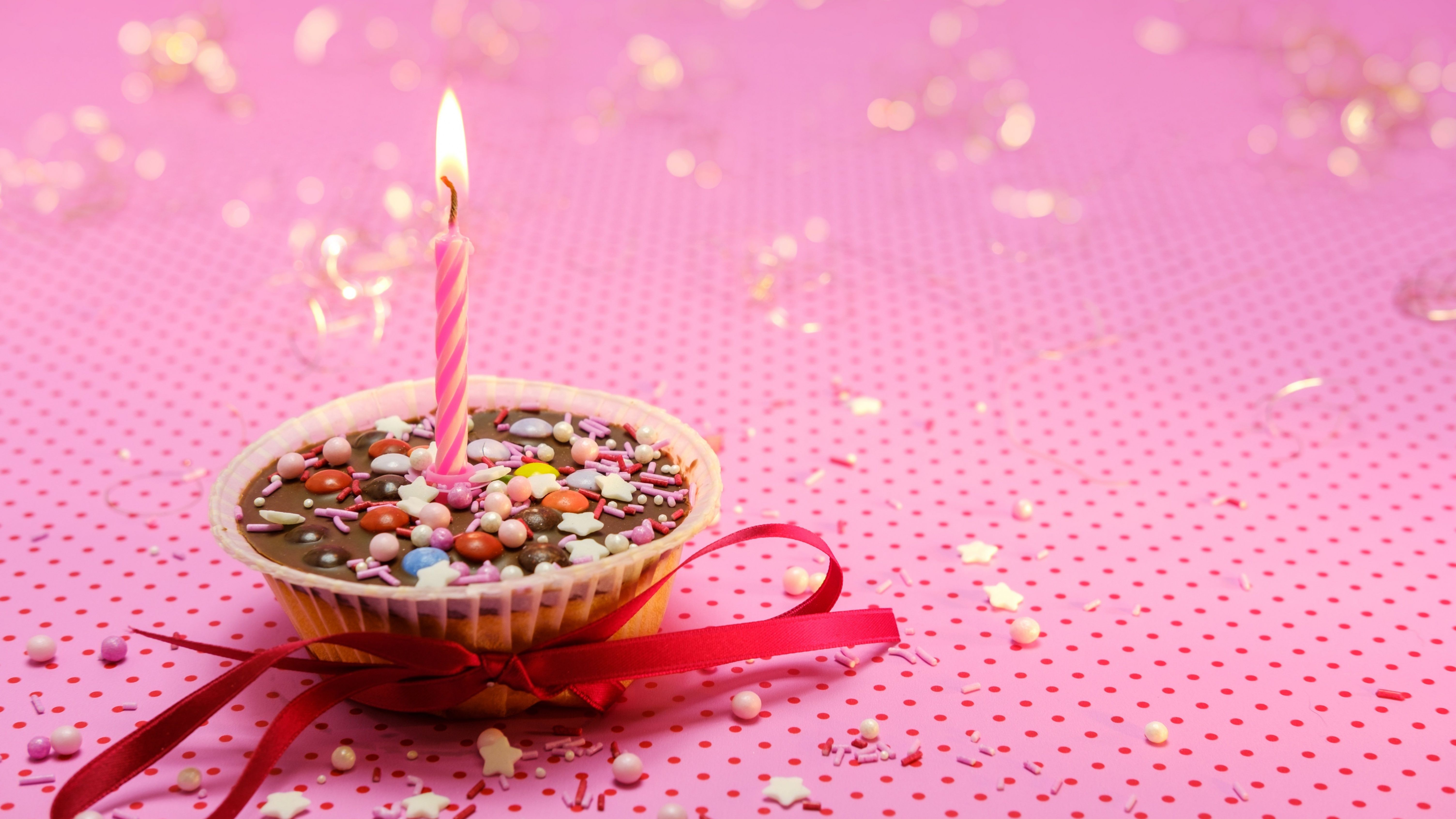 A birthday cake with one candle on a pink background - 