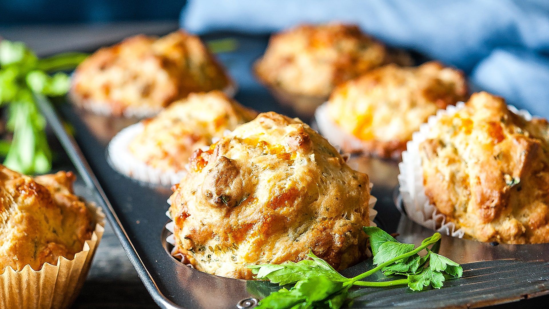 A muffin tray with a blue napkin in the background. - 