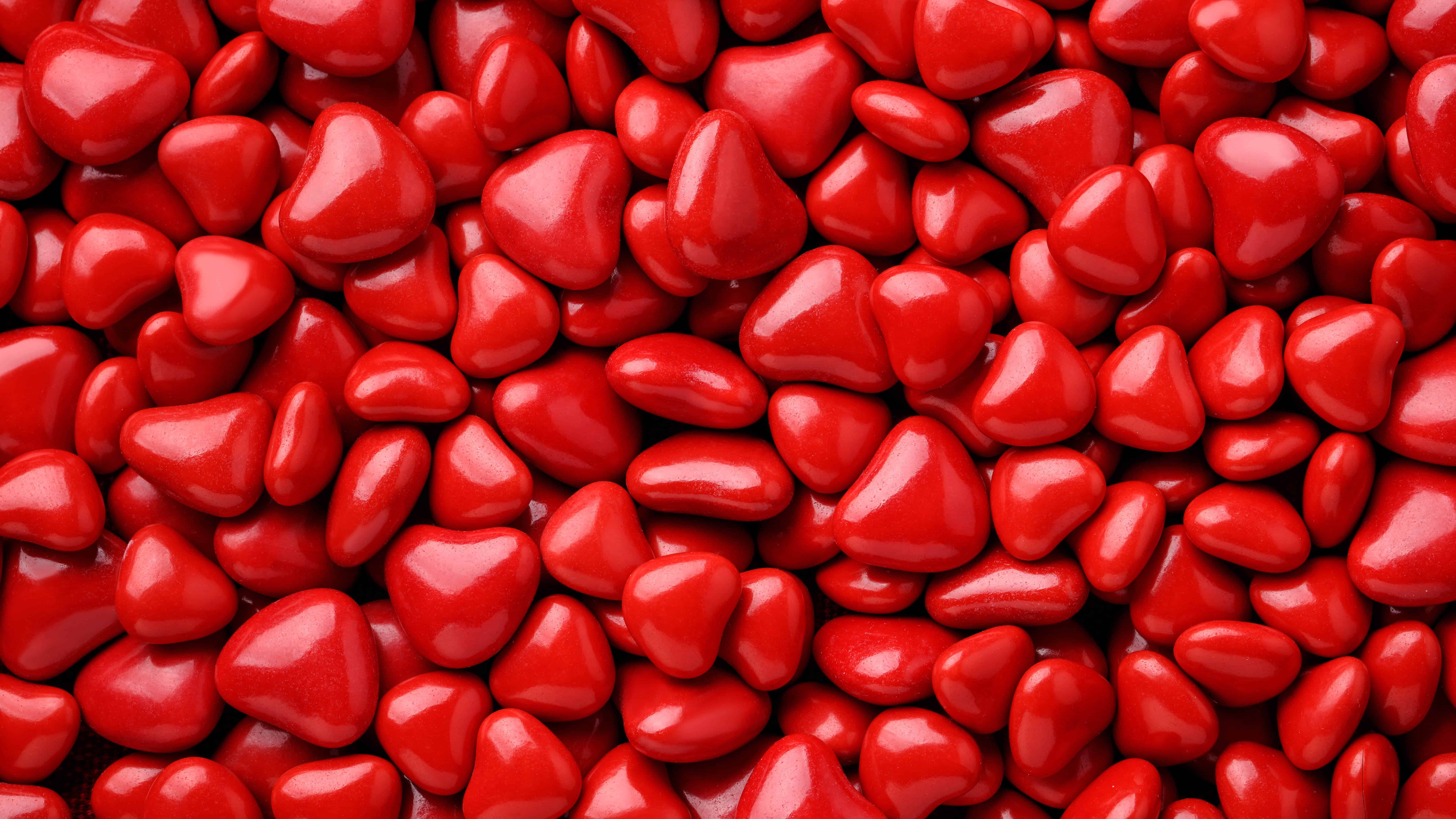 A pile of red, glossy, plastic hearts. - Candy, red