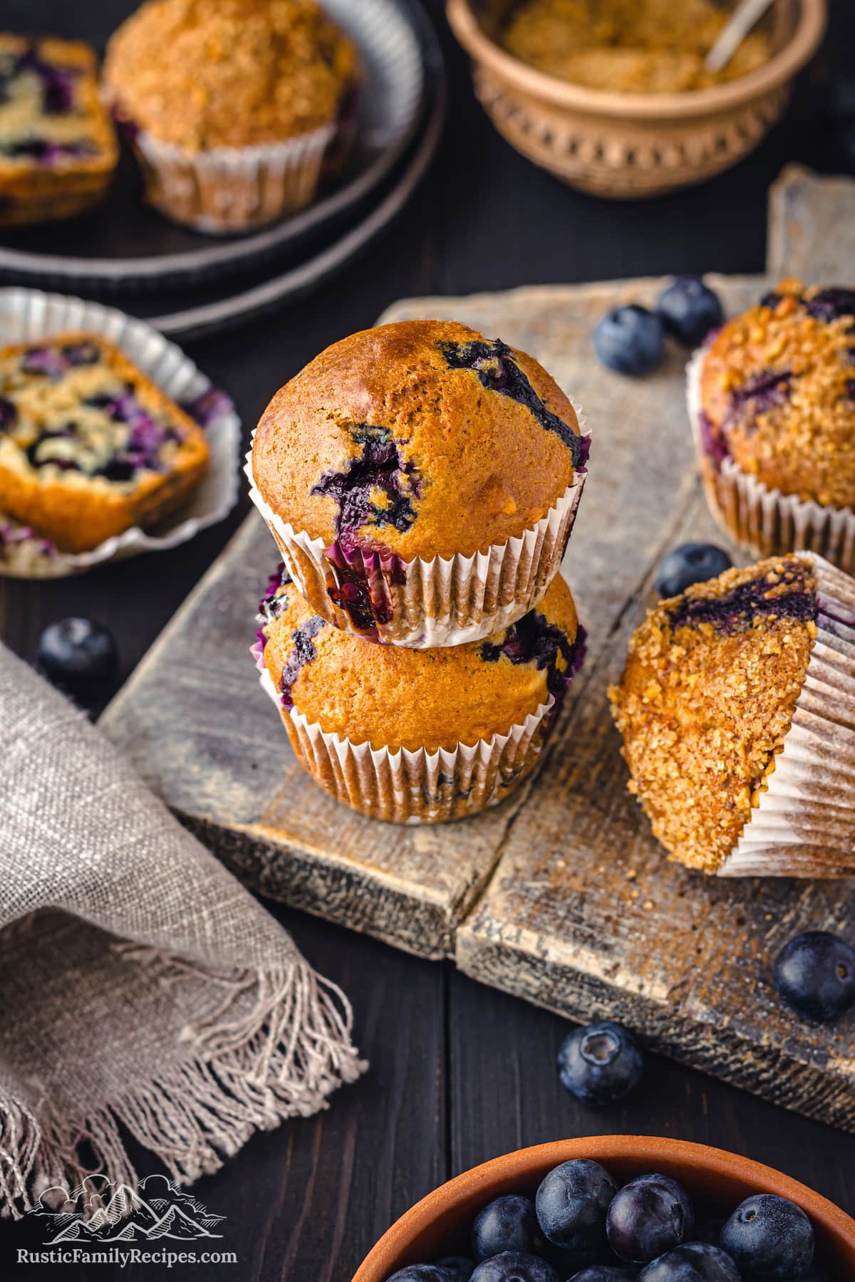 Blueberry muffins on a wooden board with a bowl of blueberries - 