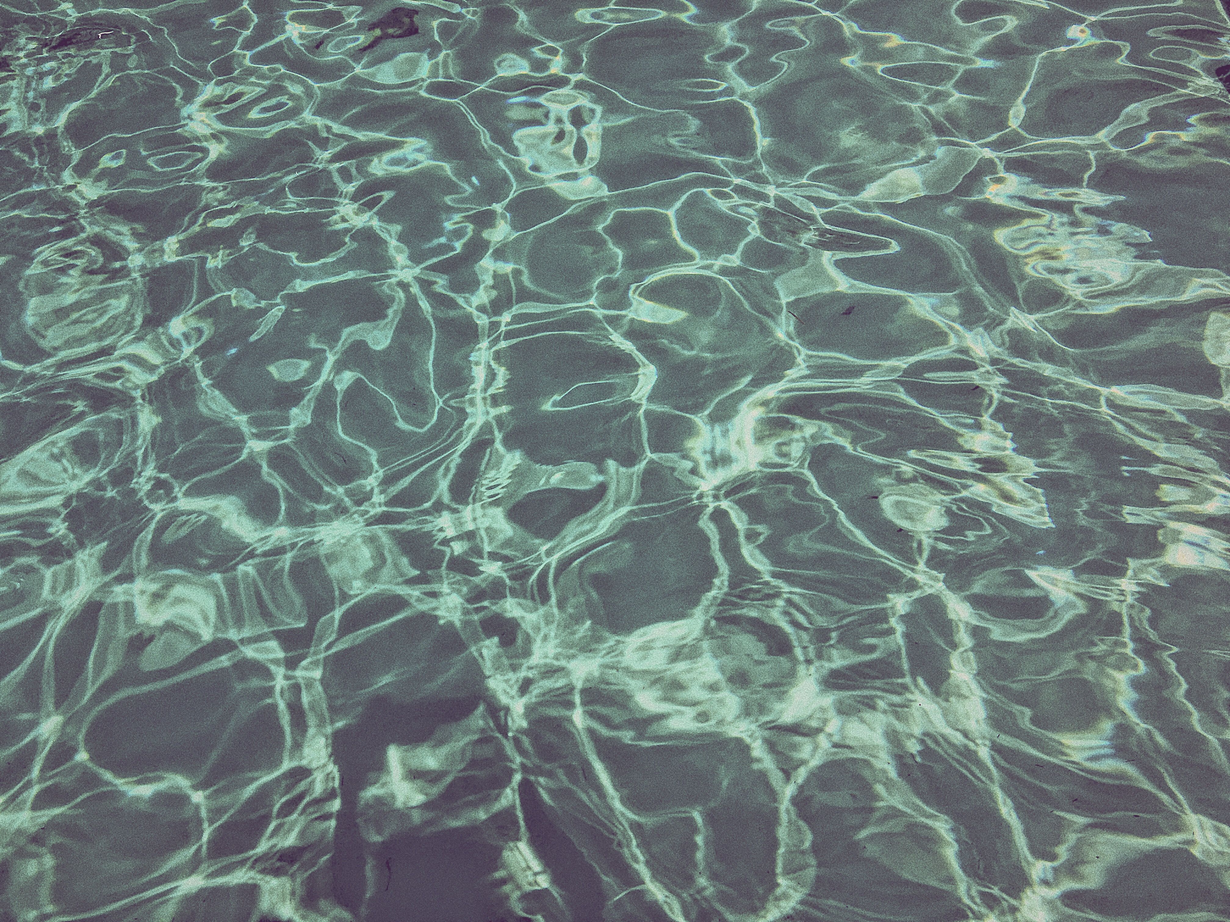 The surface of a pool, with ripples and reflections of light. - Swimming pool