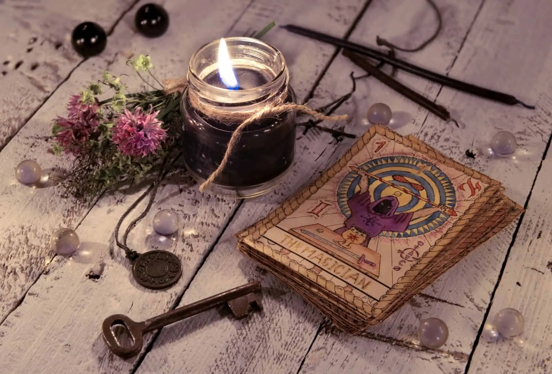 A candle burns on a table with tarot cards, flowers, and a key. - Witchcore
