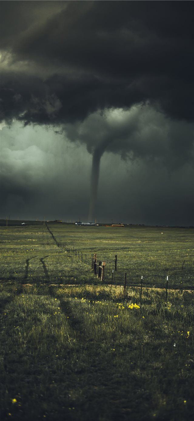 A tornado is in the distance of an open field - Storm