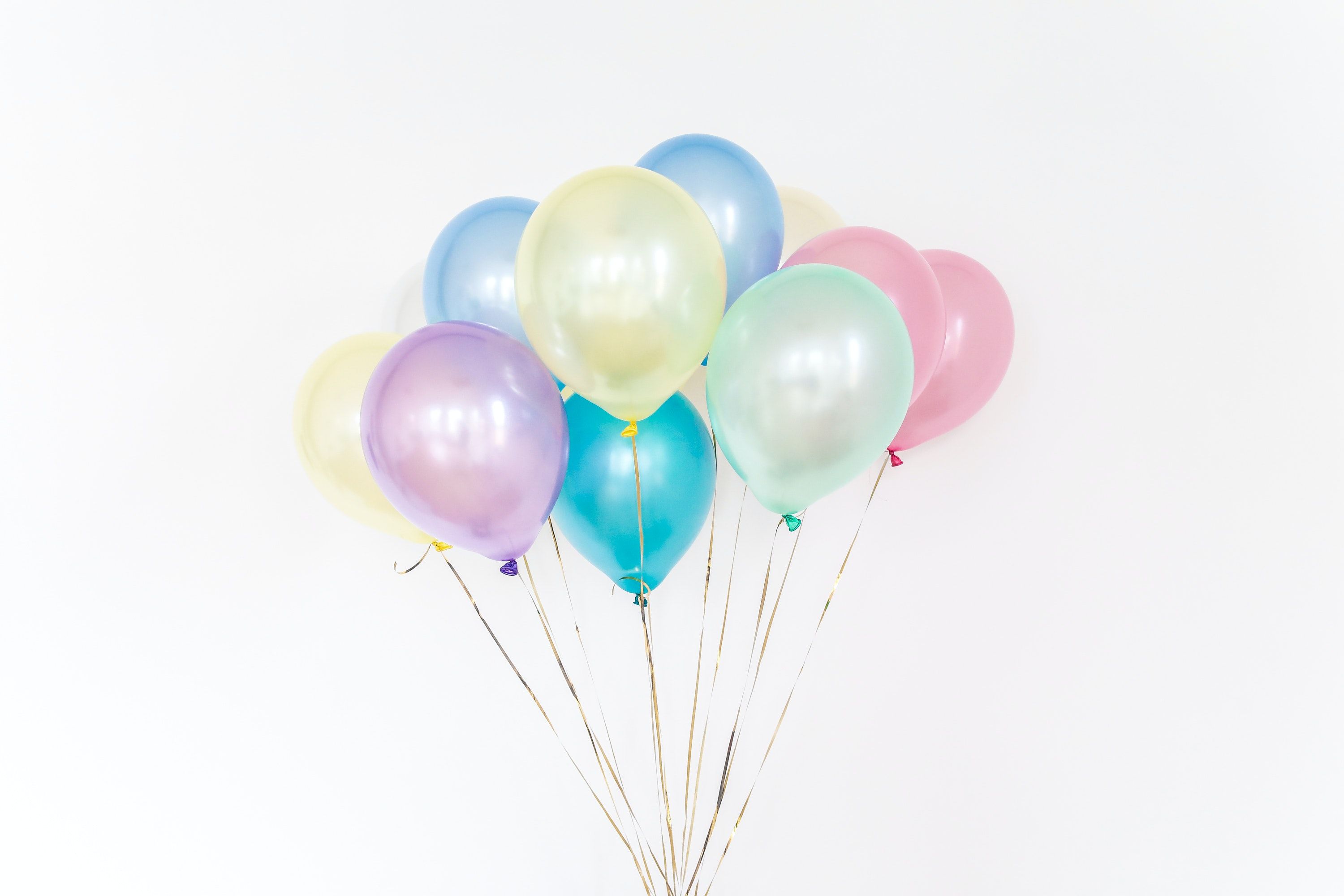 A bunch of pastel colored balloons on a white background - Balloons