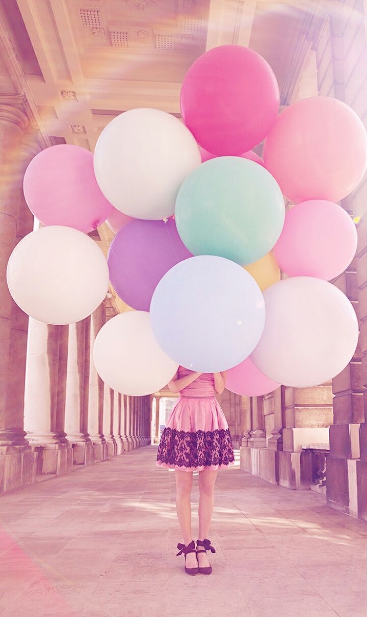 A girl holding up many colorful balloons - Balloons