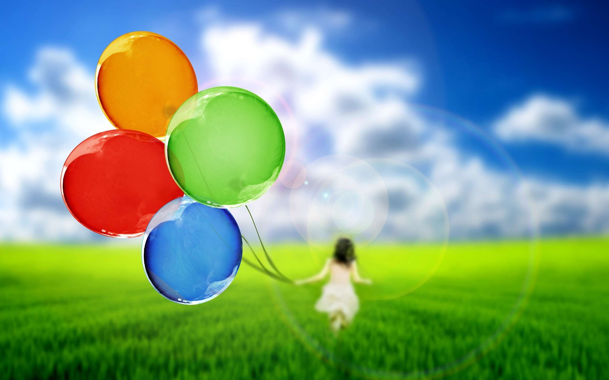 A girl in a white dress holding balloons in a green field - Balloons