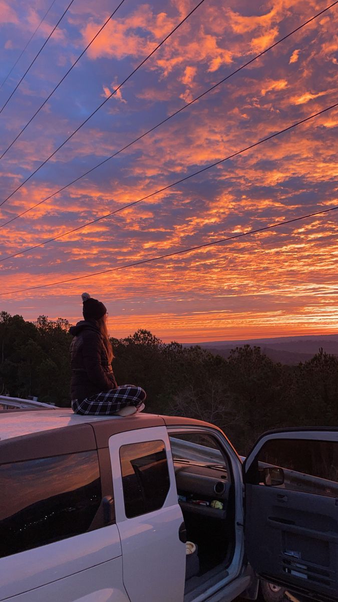A woman sitting on the back of an suv - Sunrise