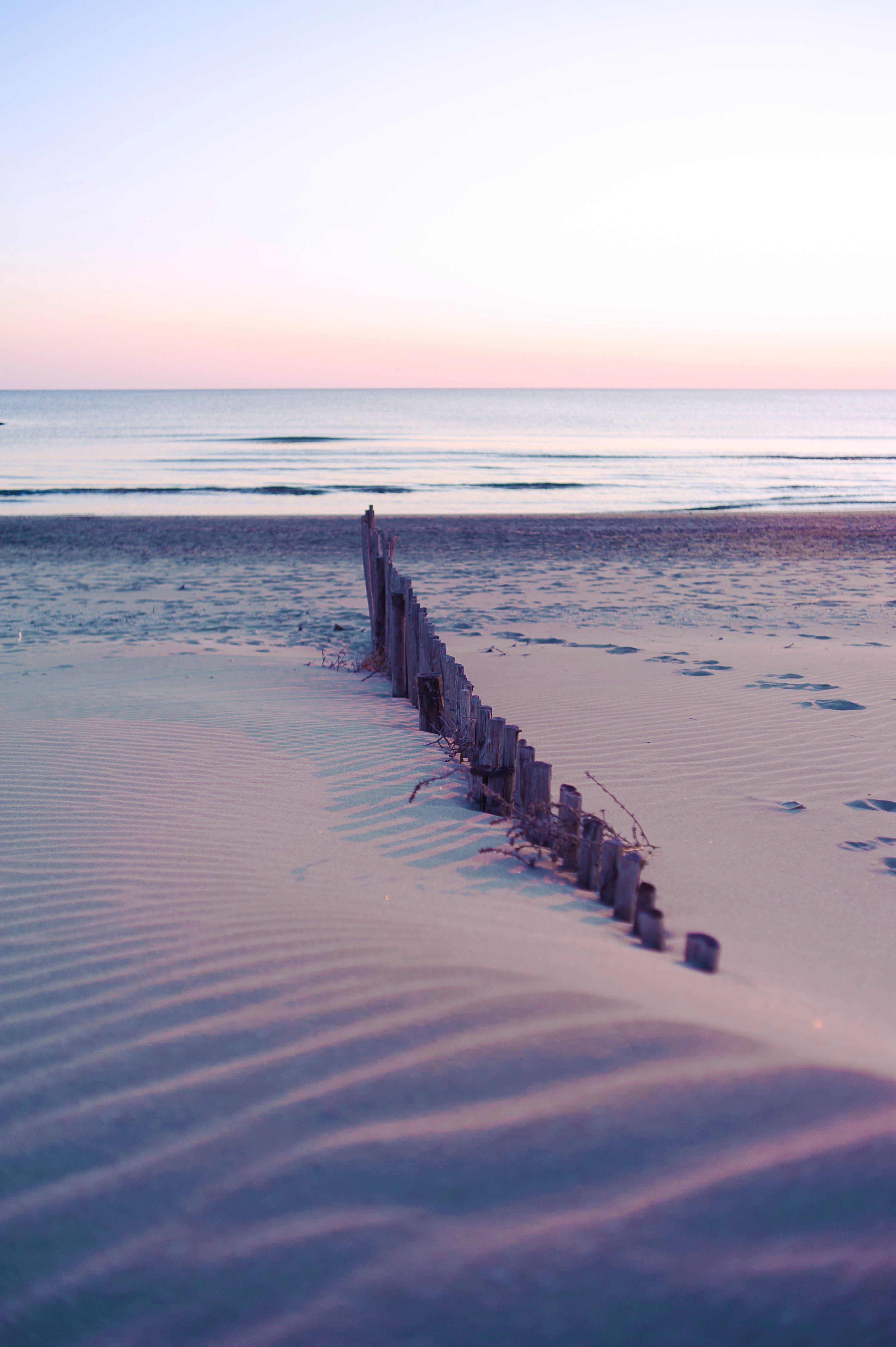 A wooden fence is on the beach - Sunrise