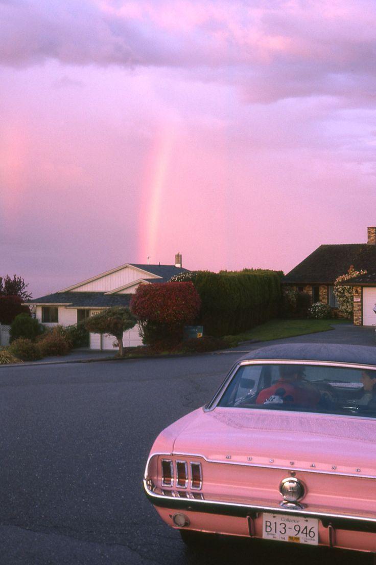A car on a street with a rainbow in the background - Cars