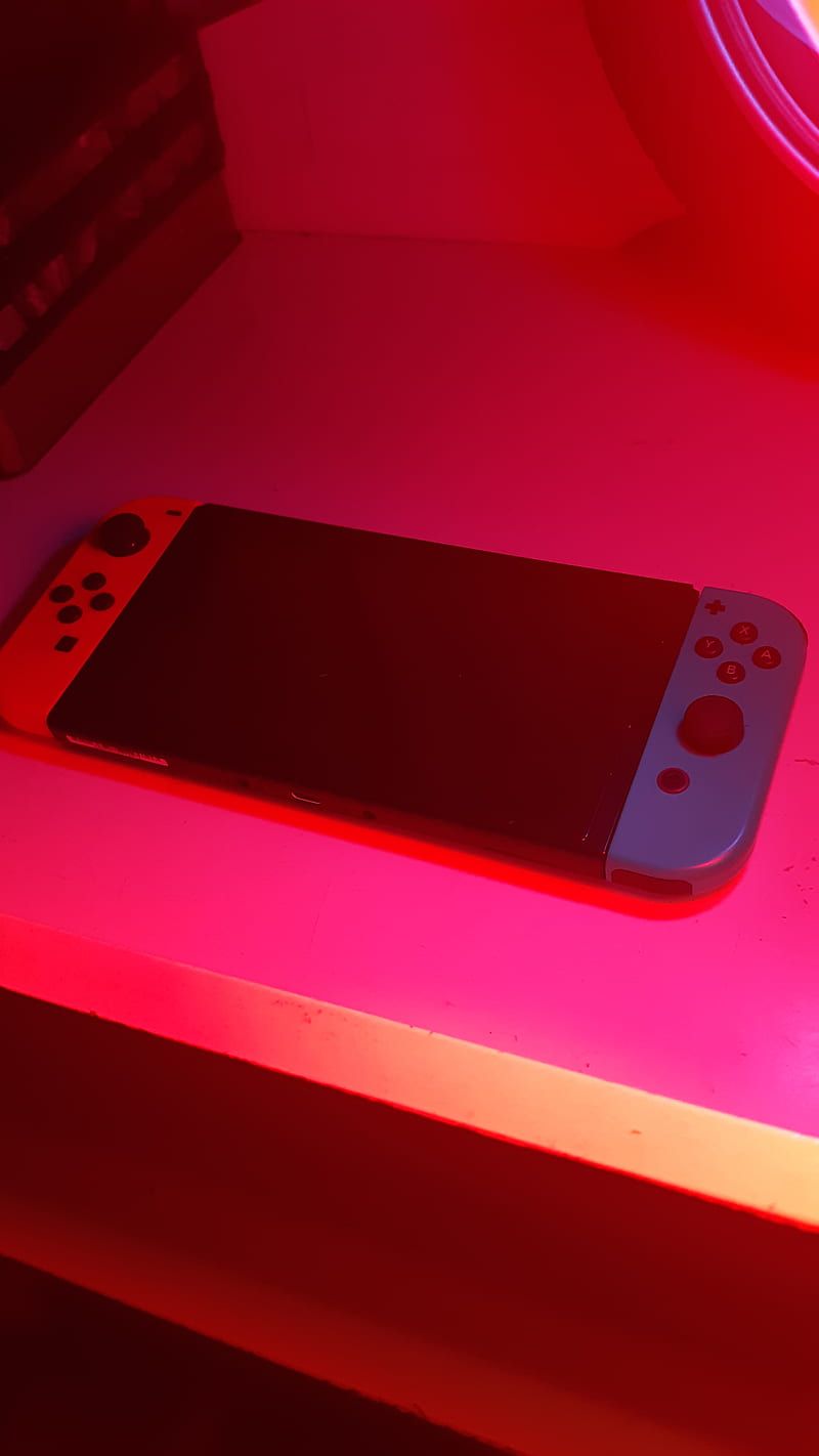 A Nintendo Switch console with neon pink lighting. - Nintendo