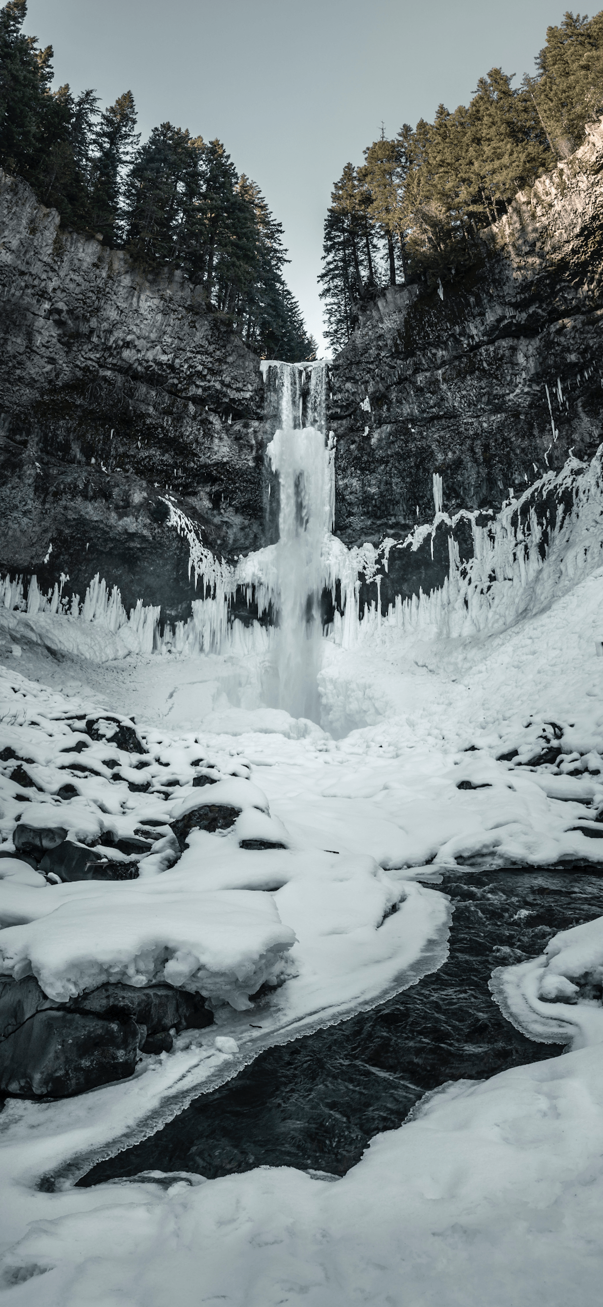 A frozen waterfall surrounded by snow and ice. - Waterfall