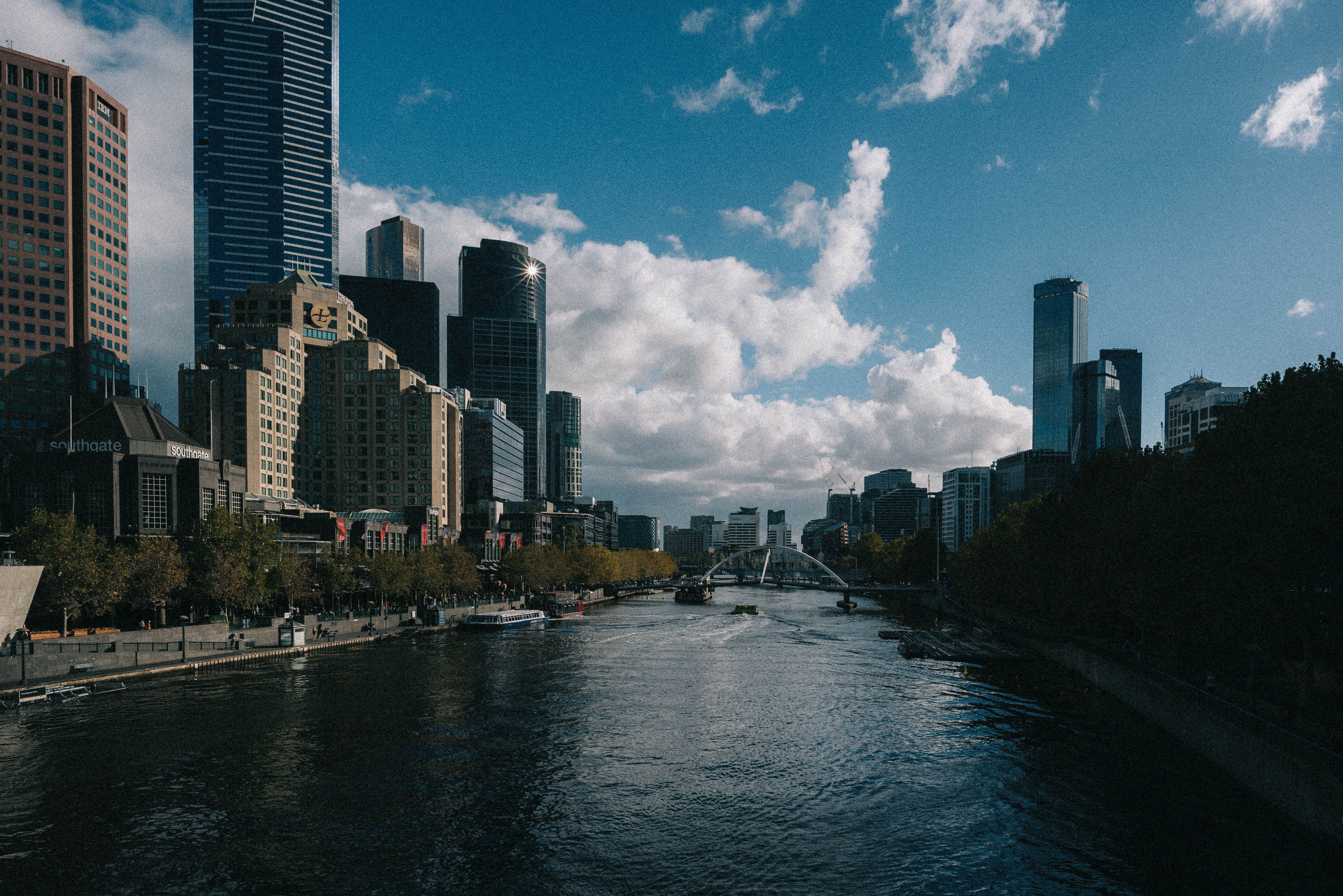 A river flows through a city with tall buildings on either side. - Cityscape