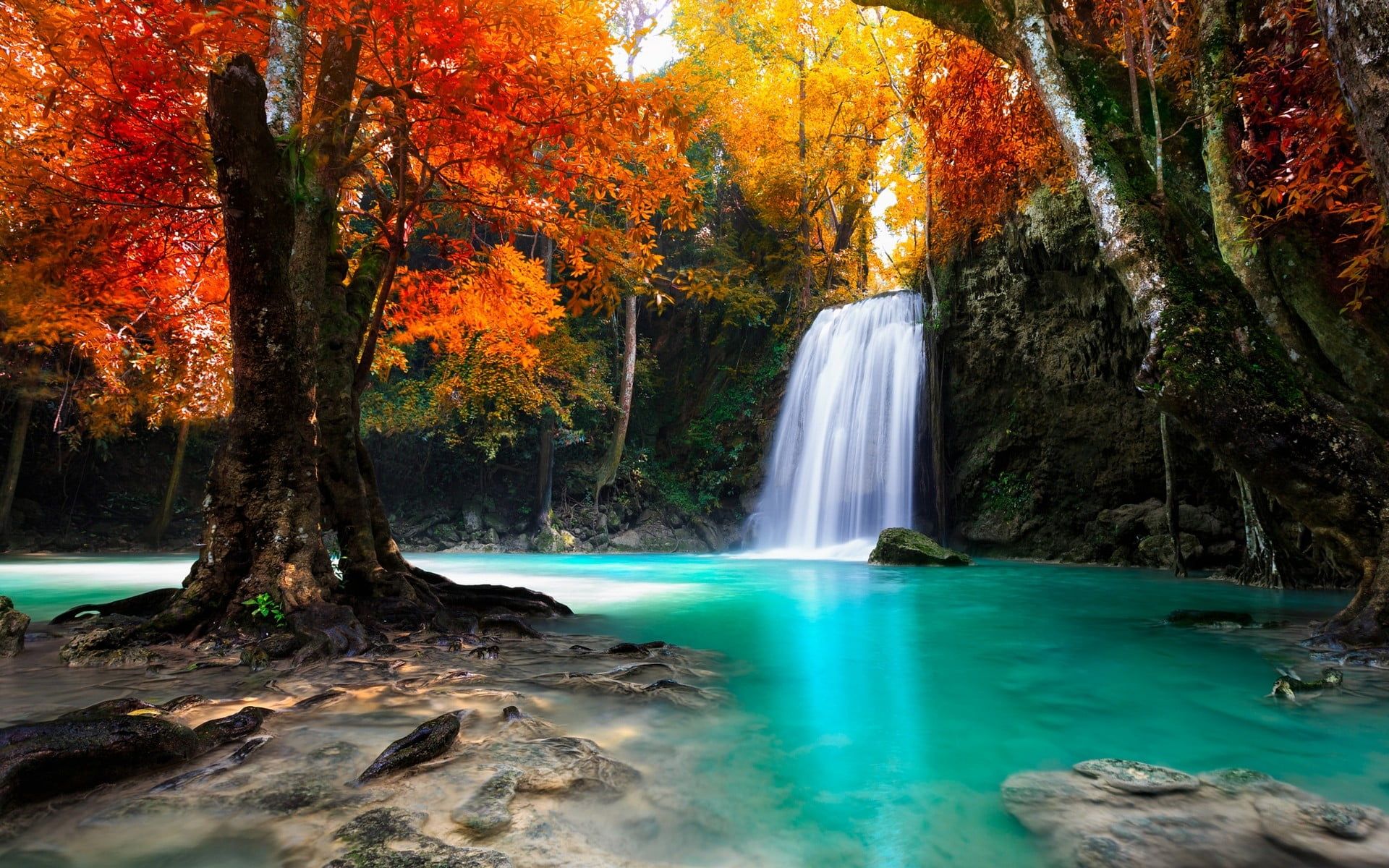 A waterfall surrounded by trees and blue waters - Waterfall