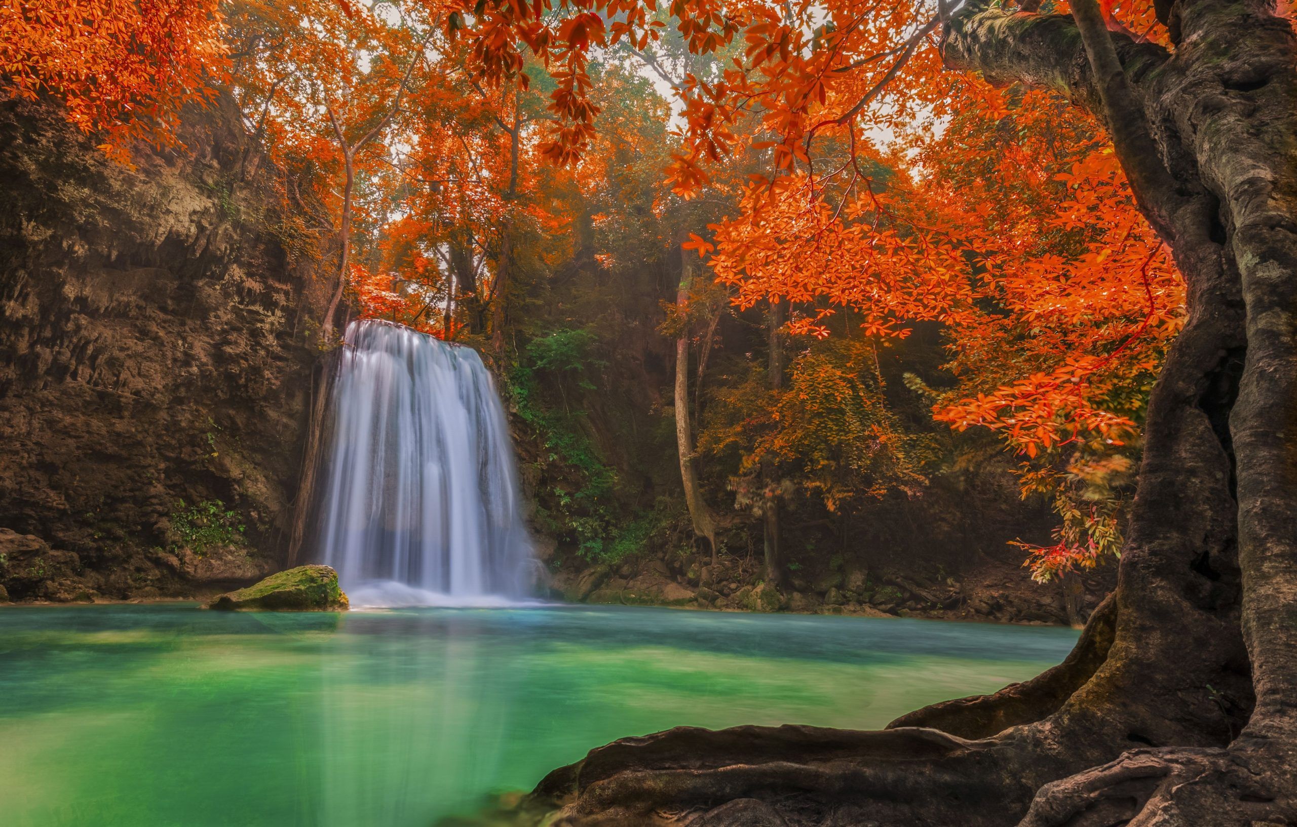 A waterfall surrounded by orange and red leaves. - Waterfall