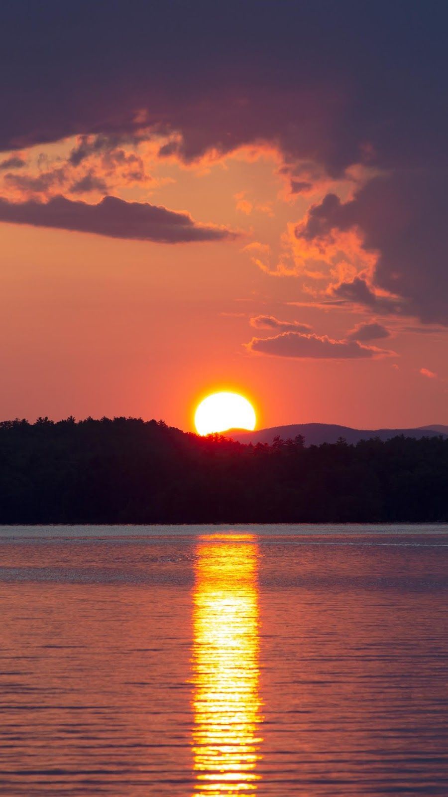 A sunset over the water with trees in background - Lake