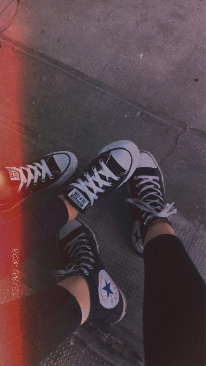 A person wearing black and white converse shoes. - Converse