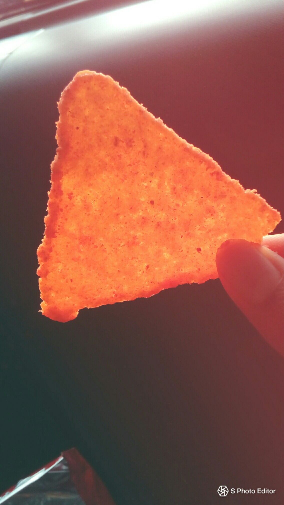 A person holding up some orange chips - Doritos