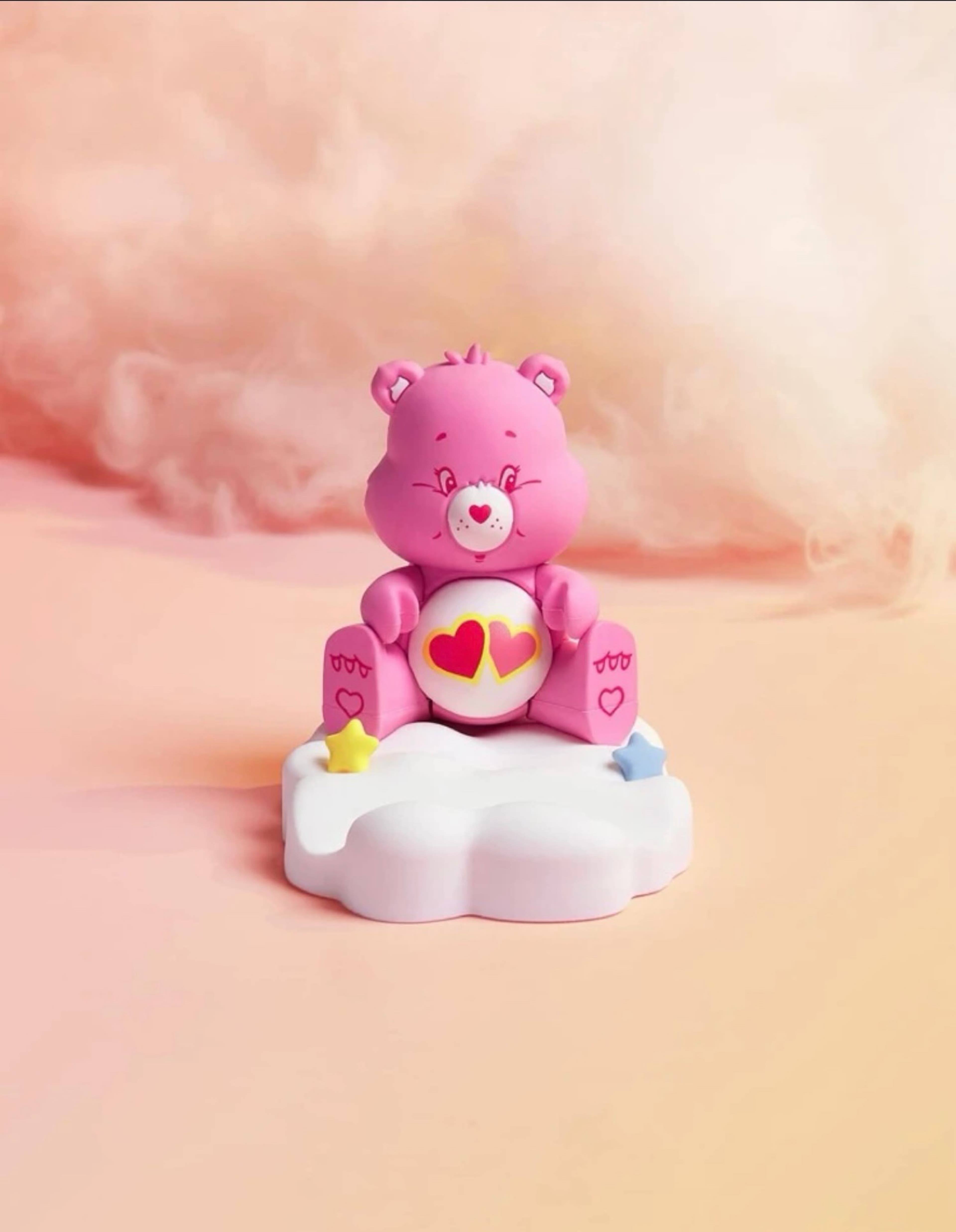 A pink teddy bear sitting on top of clouds - Care Bears