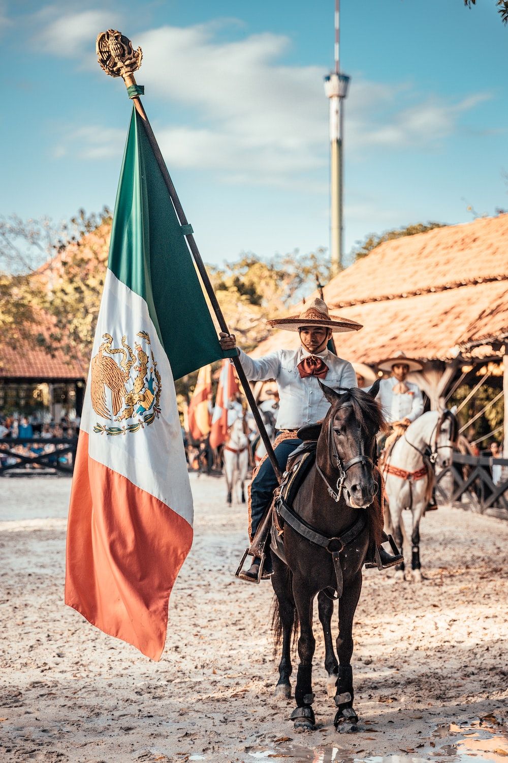 A man riding a horse holding a Mexican flag - Mexico