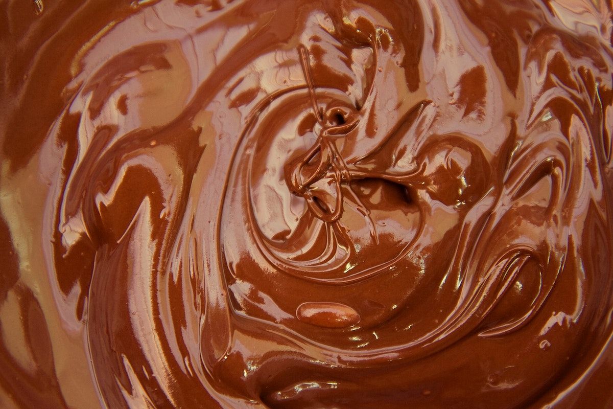 A close up of chocolate being swirled in a bowl. - Chocolate