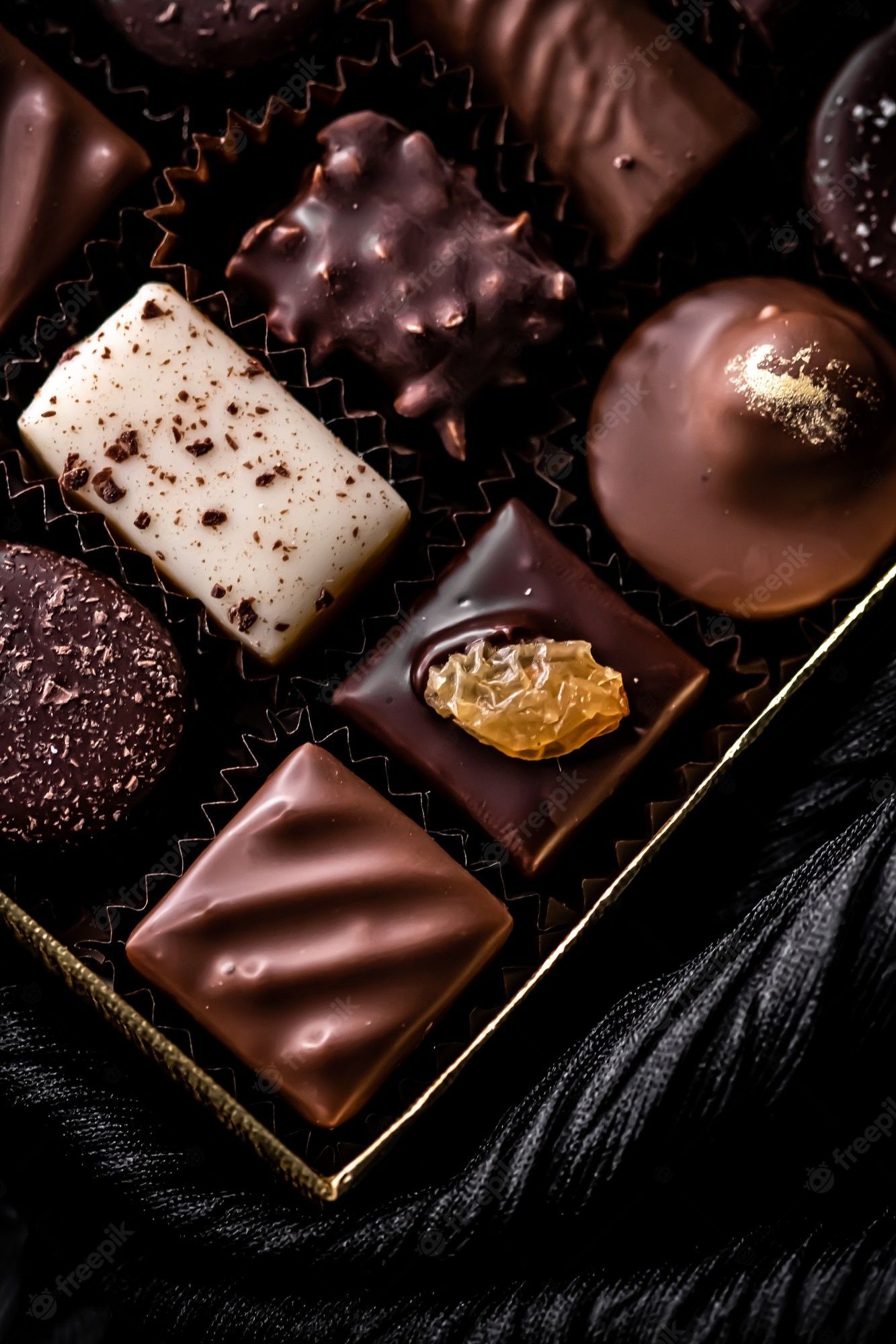 Assorted chocolates in a box on a black background - Chocolate