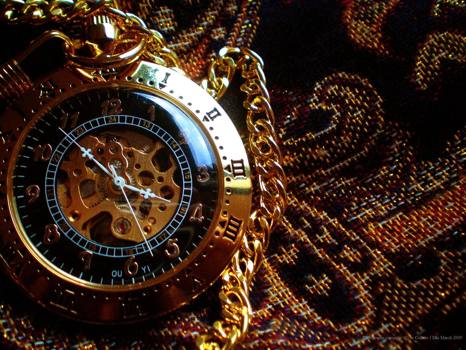 A gold watch with a chain on a plaid background. - Steampunk