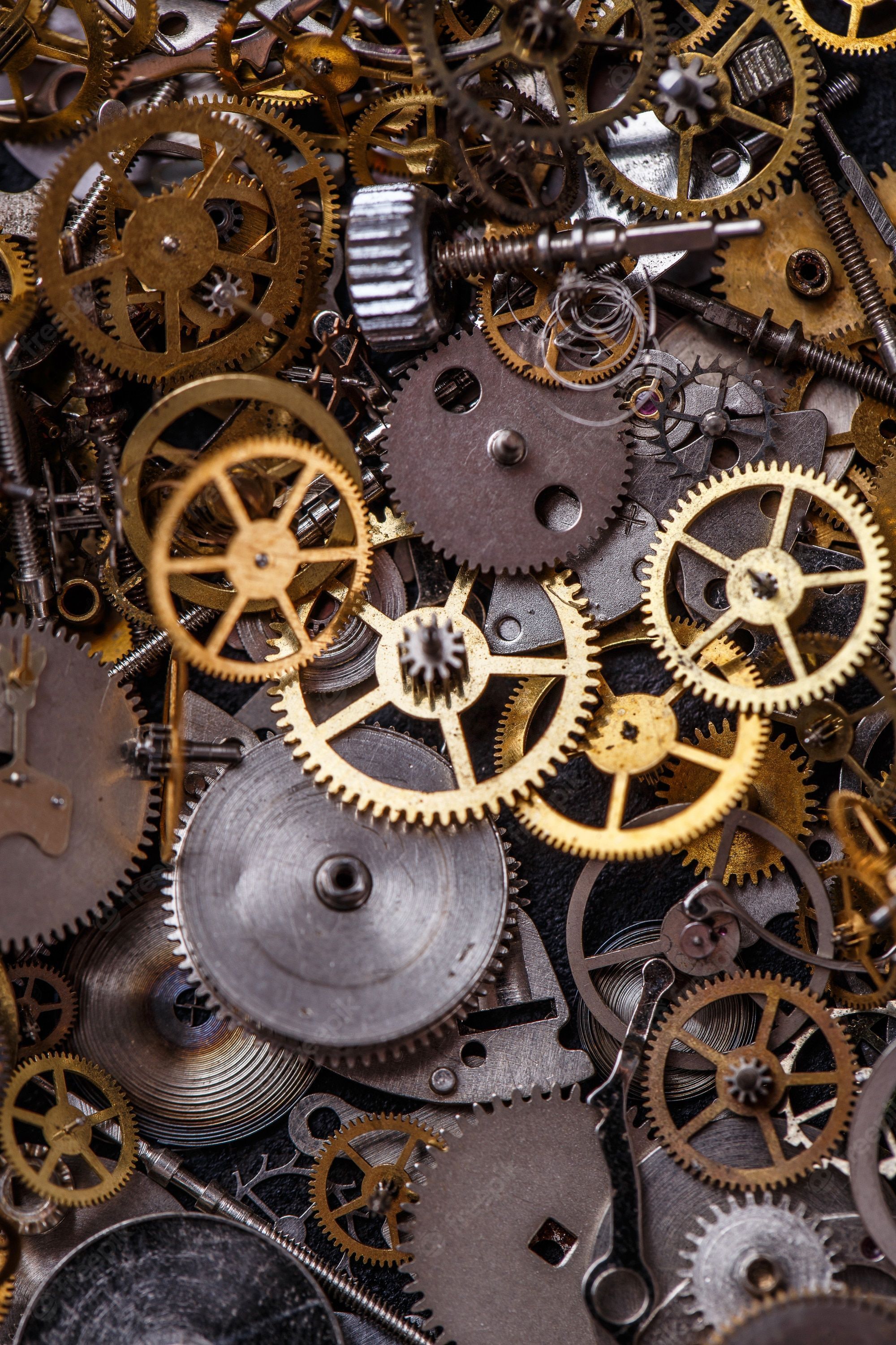 A close up of a pile of watch parts, including gold and silver gears. - Steampunk