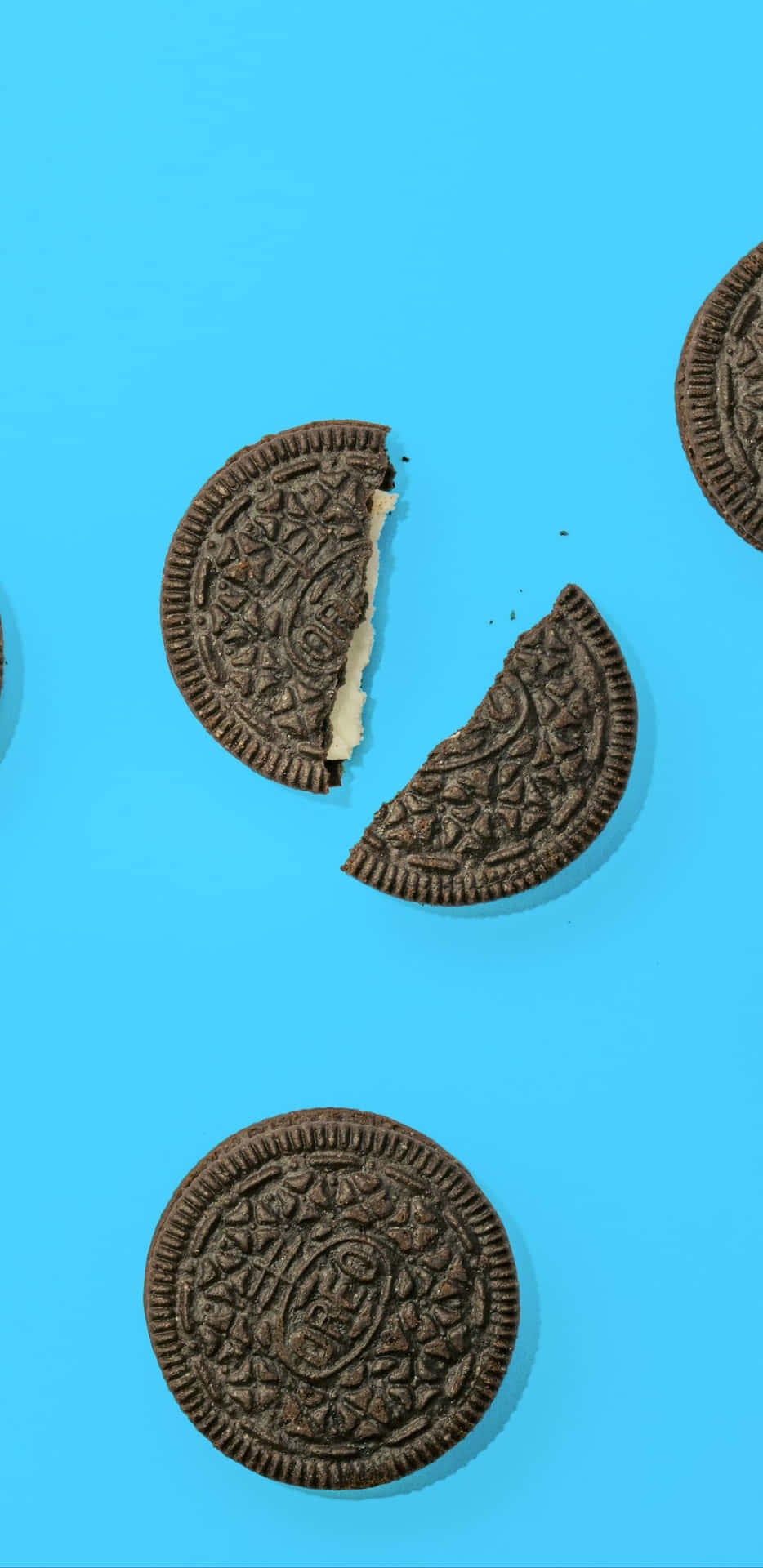 A group of Oreo cookies are arranged in a circle on a blue background. The cookies are placed in various positions, with some being partially cut or - Oreo