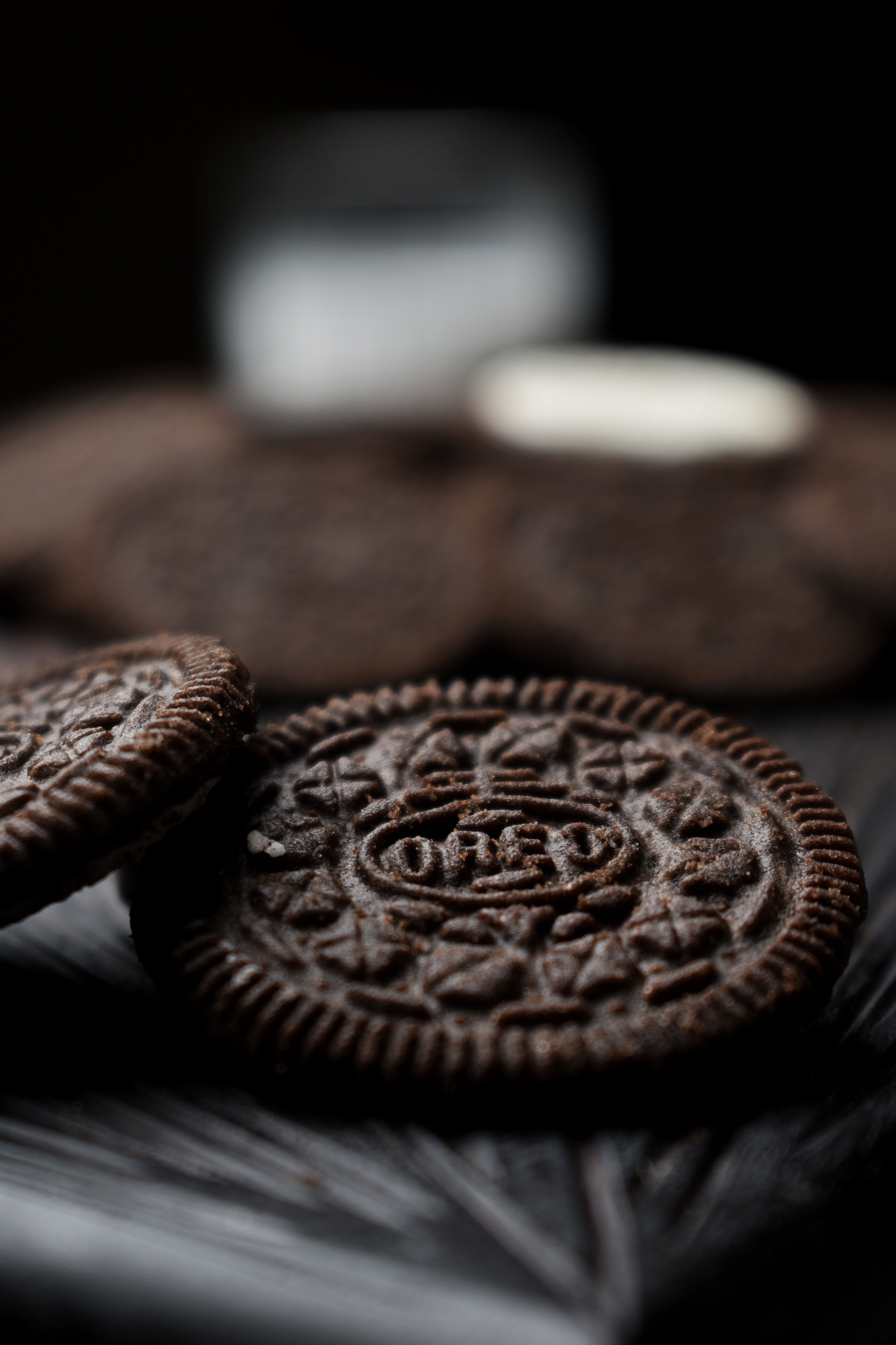 A photograph captures a close-up view of several chocolate Oreo cookies arranged on a black surface. The cookies are placed in a row - Oreo