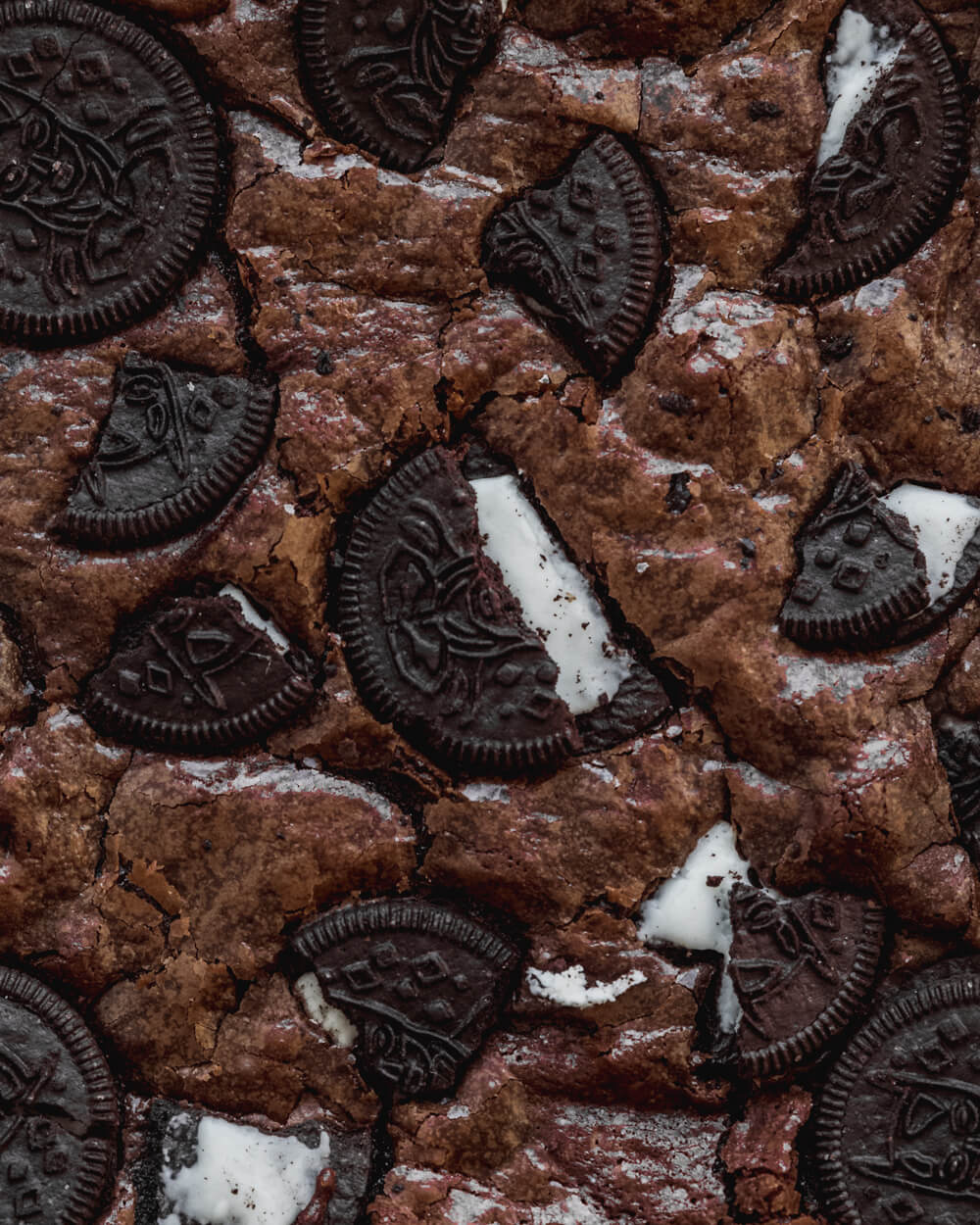 A close up of a batch of brownies with chocolate cookies on top - Oreo