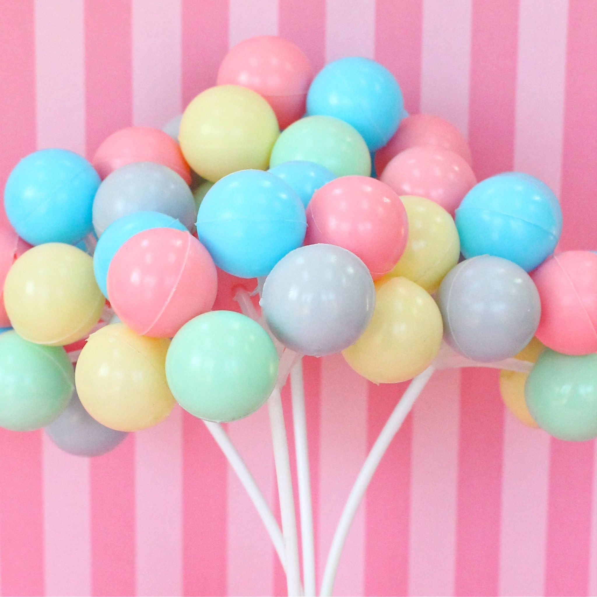 A bunch of balloons on sticks in front of a pink background - Balloons