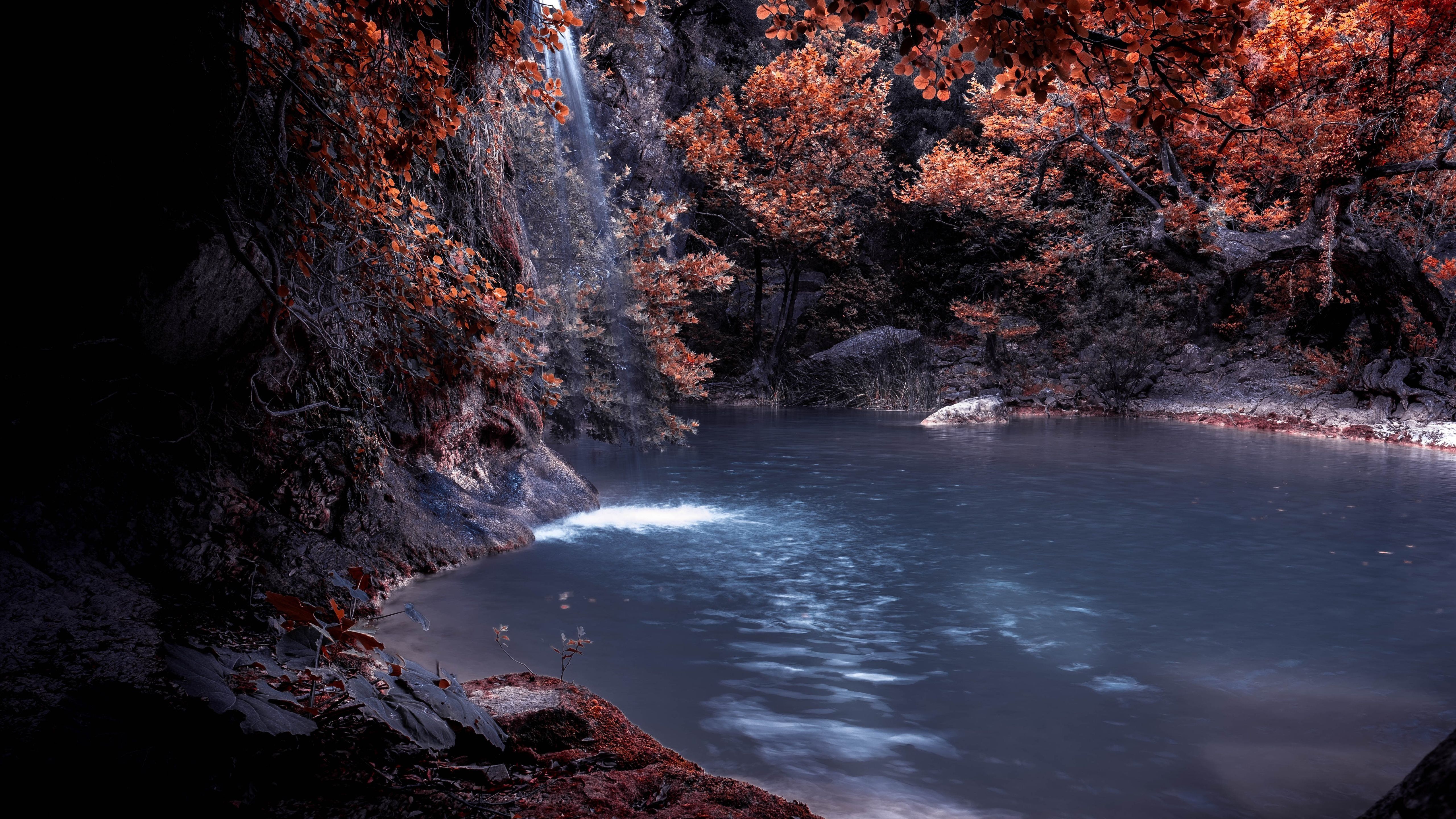 A river surrounded by trees with red leaves. - Waterfall