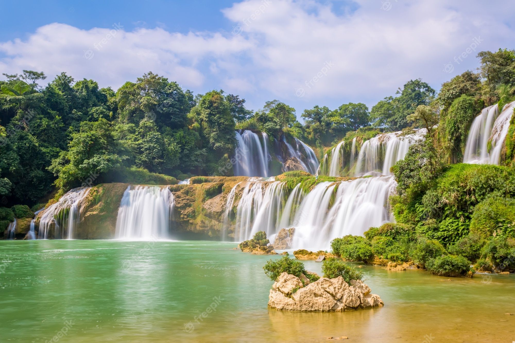 A waterfall in the middle of green trees - Waterfall