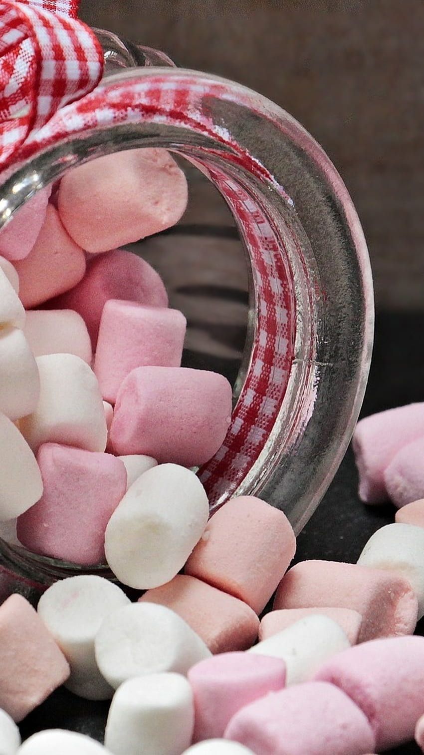 Pink and white marshmallows spilling out of a jar. - Marshmallows