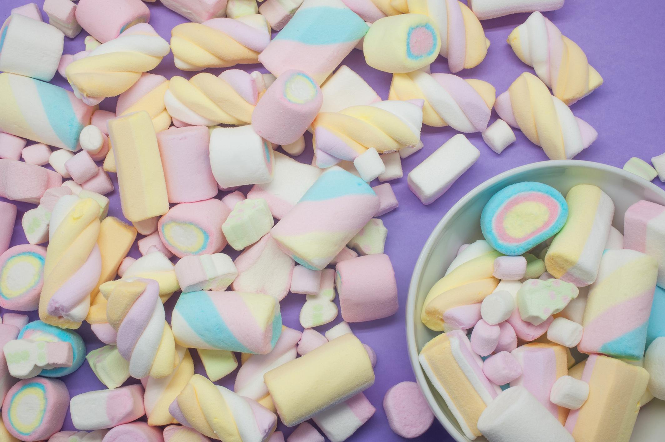 Marshmallows of different colors and sizes on a purple background - Marshmallows