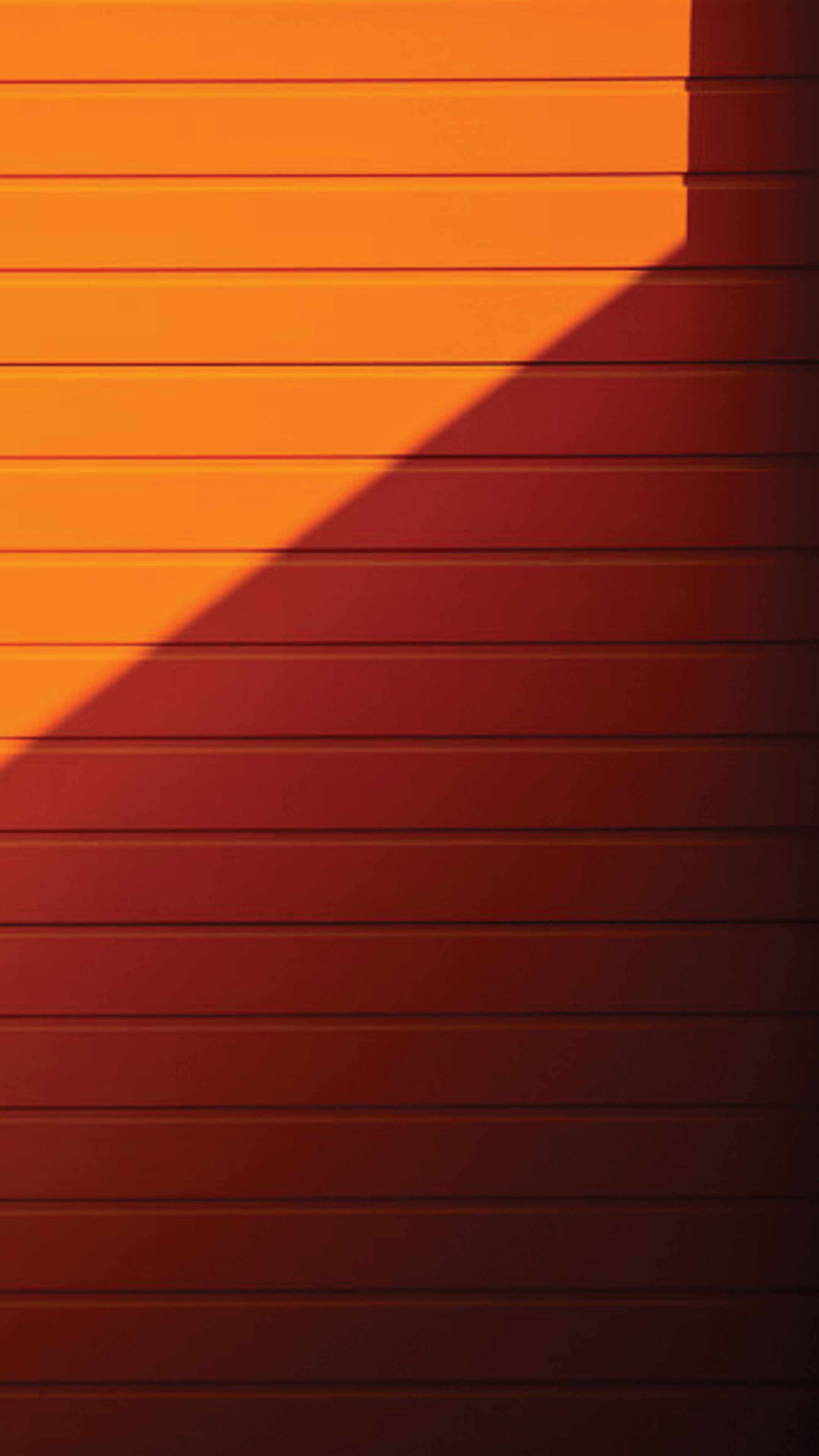 An orange and red sunset casts a shadow on a red wall. - Orange