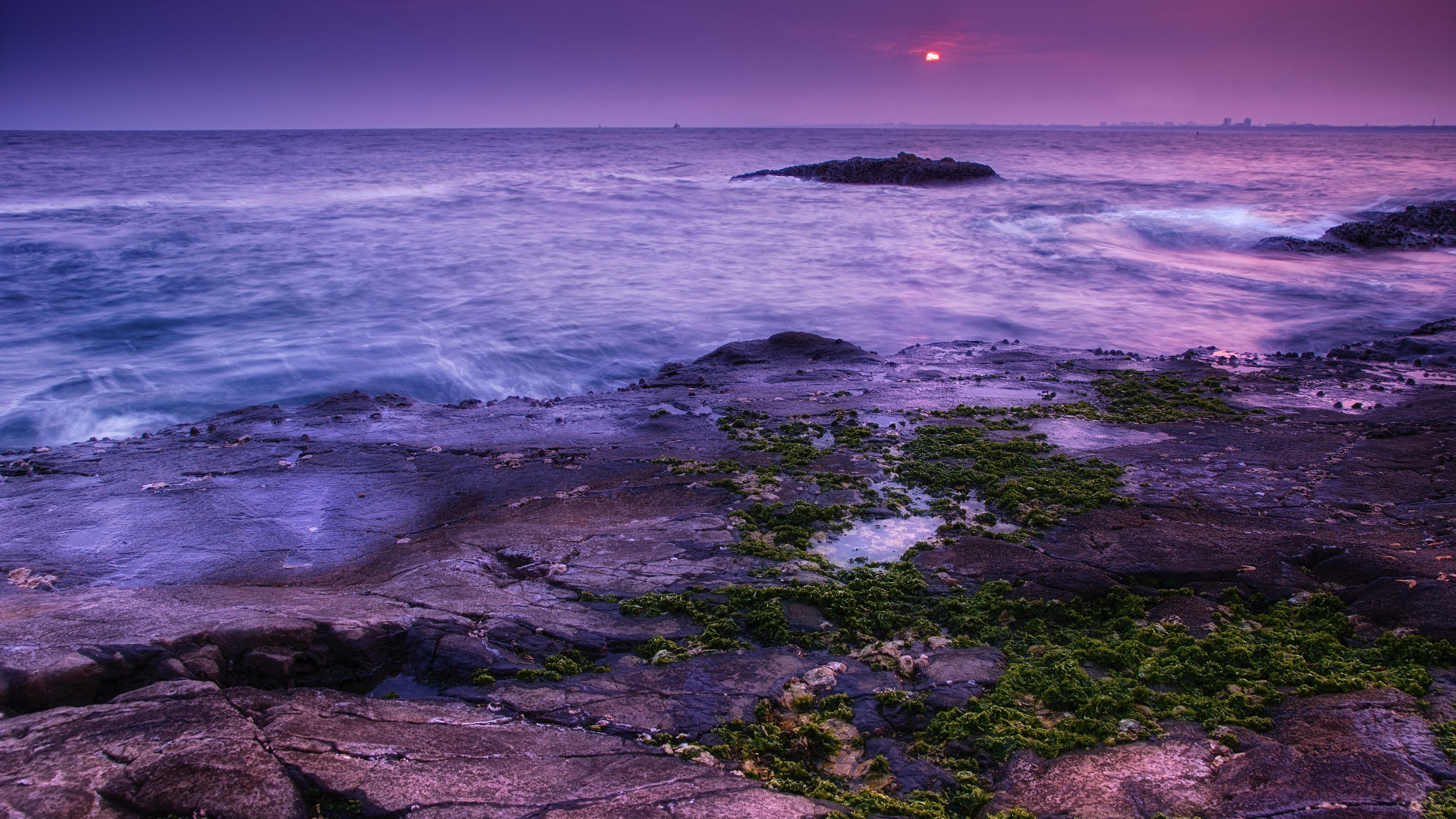 A rocky shore with water and the sun setting - Sunset