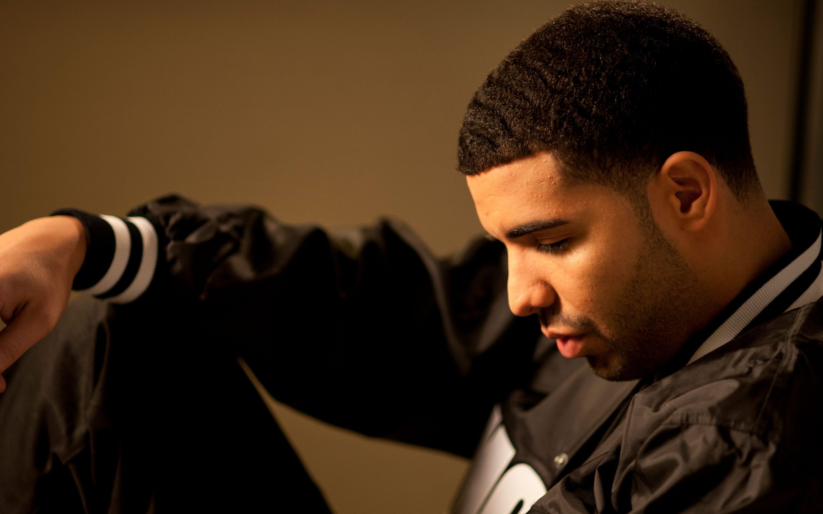 Drake in a black jacket with white stripes on the sleeves. - Drake