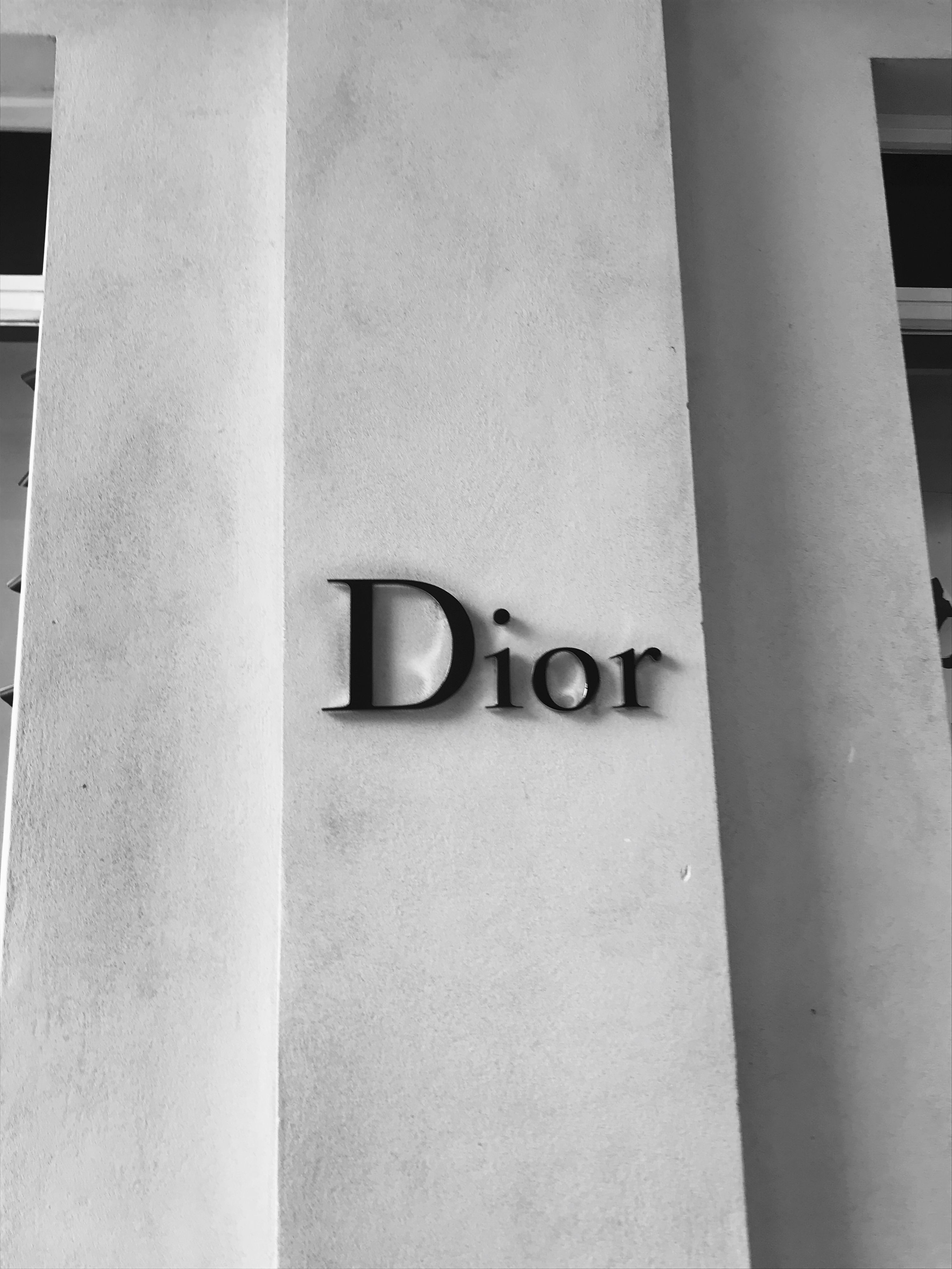 A black and white photo of a Dior sign on a pillar - Dior