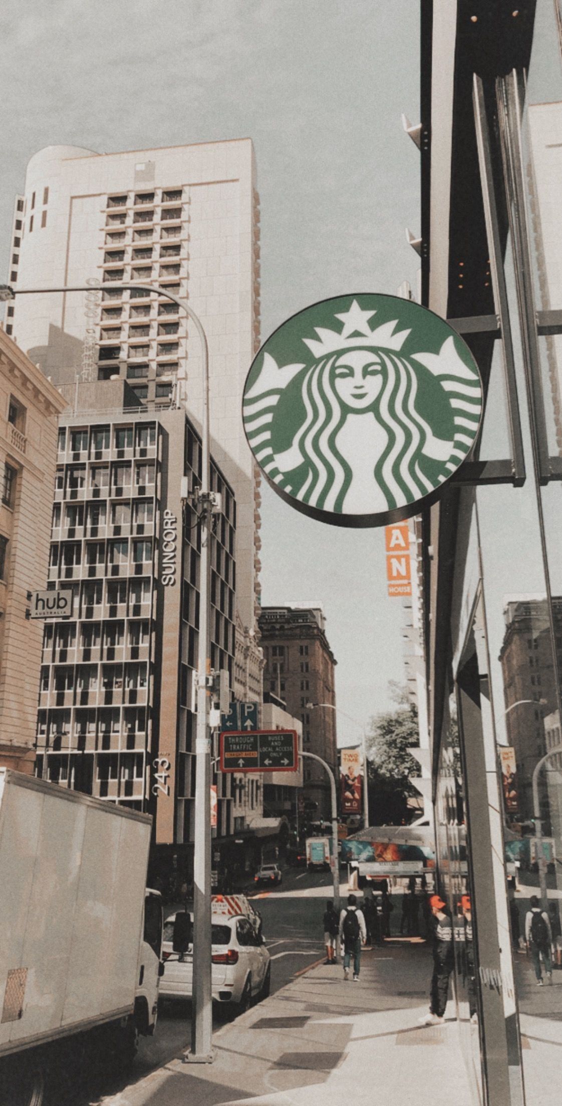 A Starbucks sign is hanging off the side of a building. - Starbucks